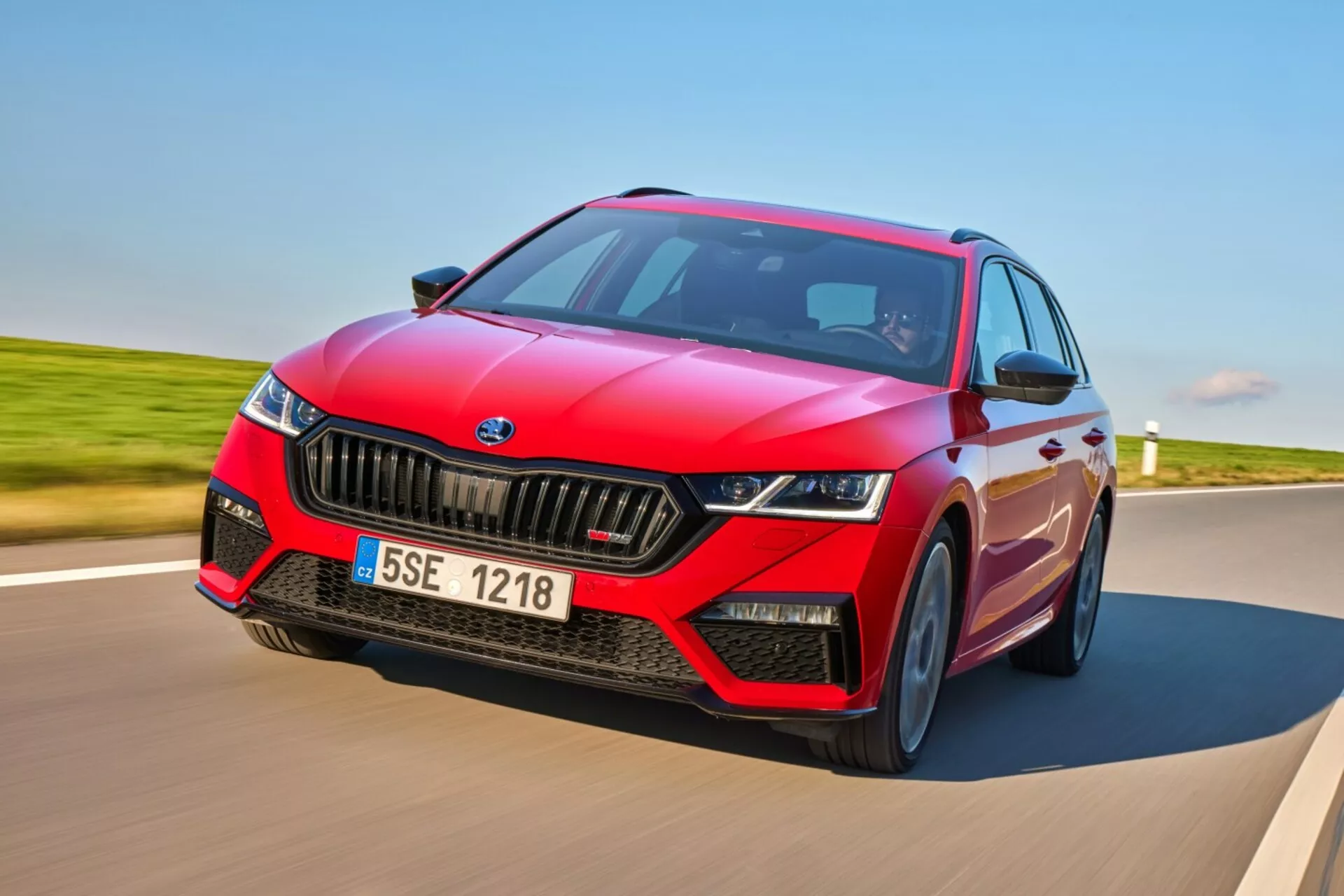 Skoda Octavia RS hatchback 2017 w dynamicznym ruchu na utwardzonej drodze, prezentująca sportowy czerwony design z czarnymi akcentami, reflektory LED i zaawansowane funkcje technologiczne, w tym ADAS i panoramiczny dach