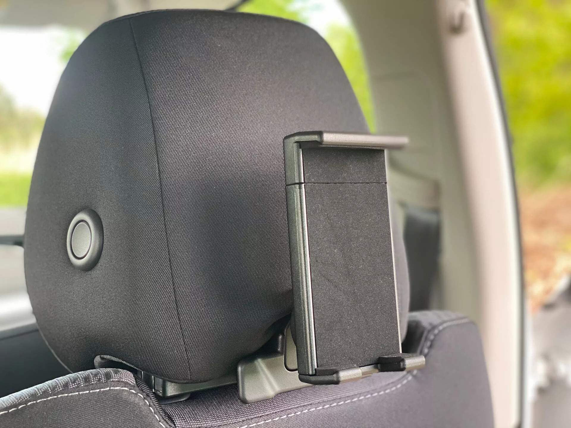 Zbliżenie zagłówka w samochodzie Škoda Octavia 2020 (Octavia-Limousine) z wnętrza pod kątem bocznym, podkreślające mechanizm regulacji zagłówka i uchwyt na płaszcz. Zagłówek ma wykończenie z tkaniny lub skóry z subtelnym wzorem, koncentrując się na komforcie i wyglądzie.