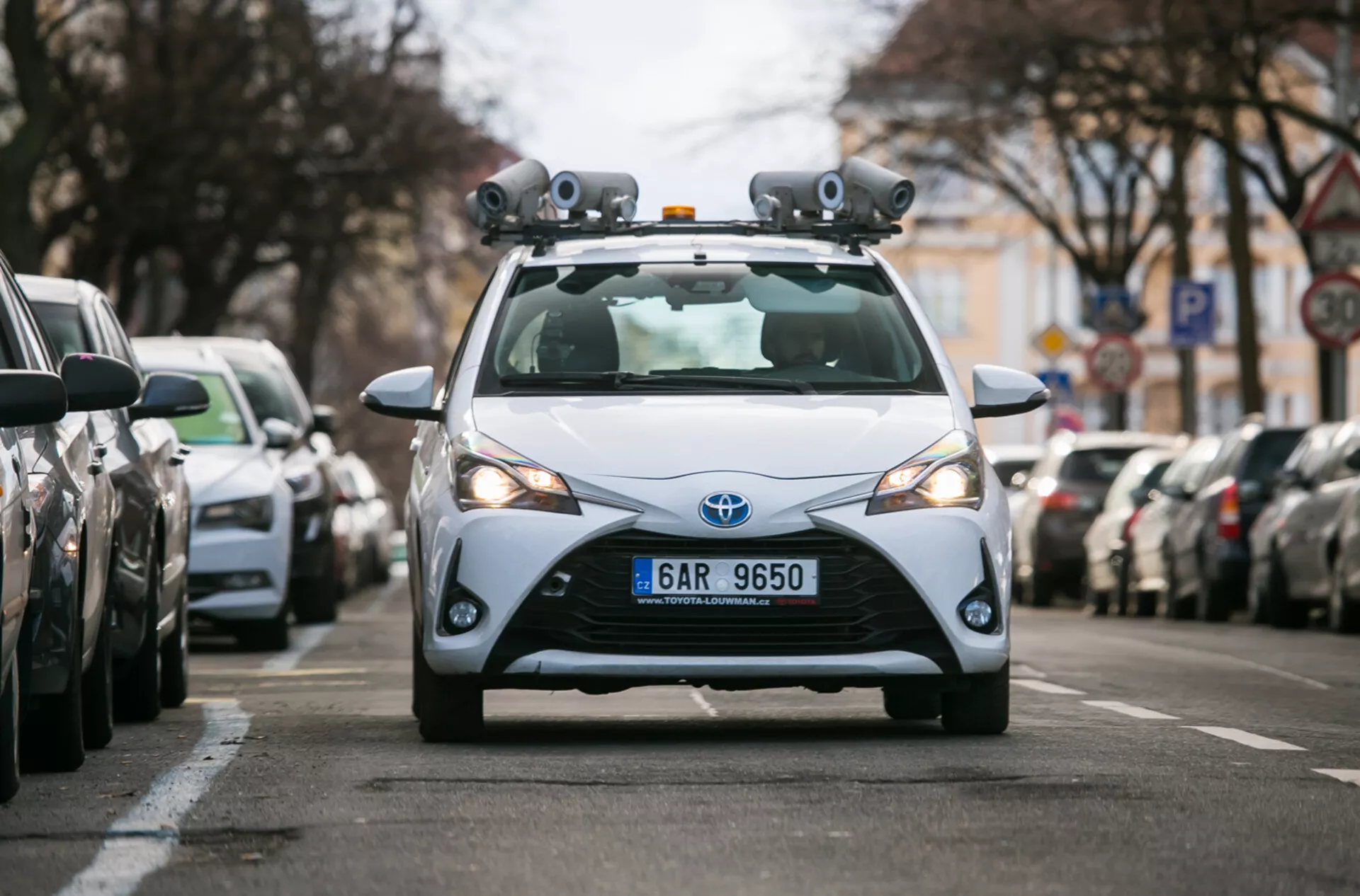 Hatchback Toyota 2017 wyposażony w czujniki LiDAR i kamery do technologii jazdy autonomicznej, uchwycony z perspektywy frontowej na miejskiej ulicy
