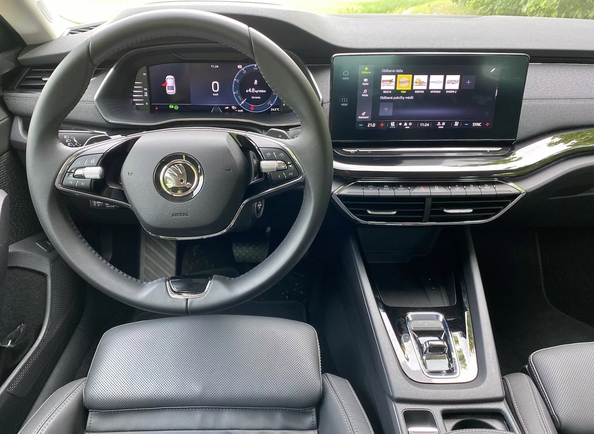 Wnętrze nowoczesnego Skoda Octavia Limousine 2020, podkreślające perspektywę kierowcy z trójramienną, wielofunkcyjną kierownicą, cyfrowym zestawem wskaźników, szerokim, poziomym ekranem dotykowym systemu infotainment, eleganckimi nawiewami i automatyczną dźwignią zmiany biegów. Luksusowe wnętrze obejmuje skórzane siedzenia i metaliczne akcenty.
