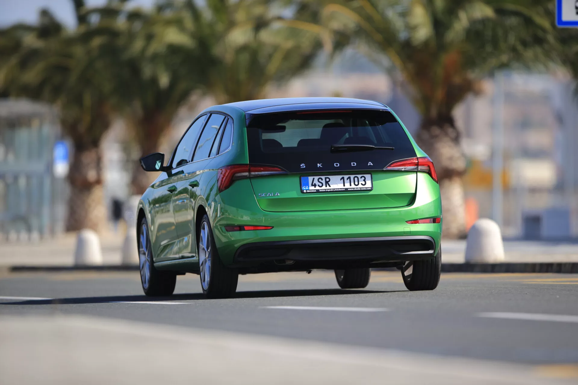 Škoda Scala 2019 w ruchu, pokazana z tyłu, prezentująca nowoczesne cechy konstrukcyjne, w tym tylne światła LED, zintegrowany spoiler i podwójne końcówki wydechu, uchwycona z dynamicznej niskiej perspektywy.