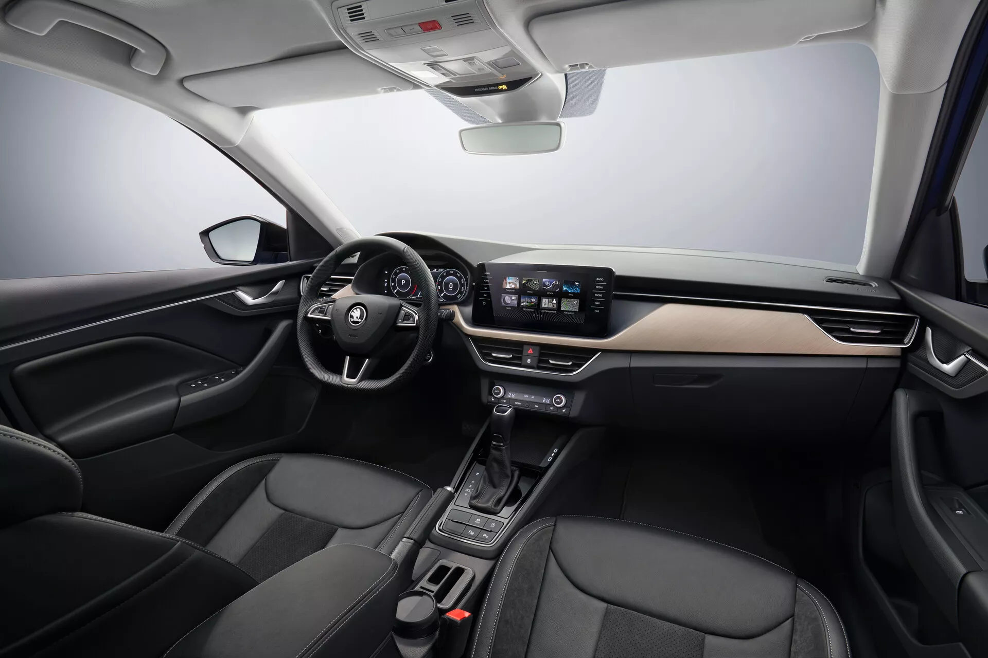 Wnętrze Skoda Scala 2019 prezentujące nowoczesny design kokpitu z akcentami z szczotkowanego metalu, centralnym systemem infotainment z ekranem dotykowym, minimalistycznymi kontroli klimatyzacji i przednimi fotelami tapicerowanymi skórą, widok z centralnego przedniego kąta.