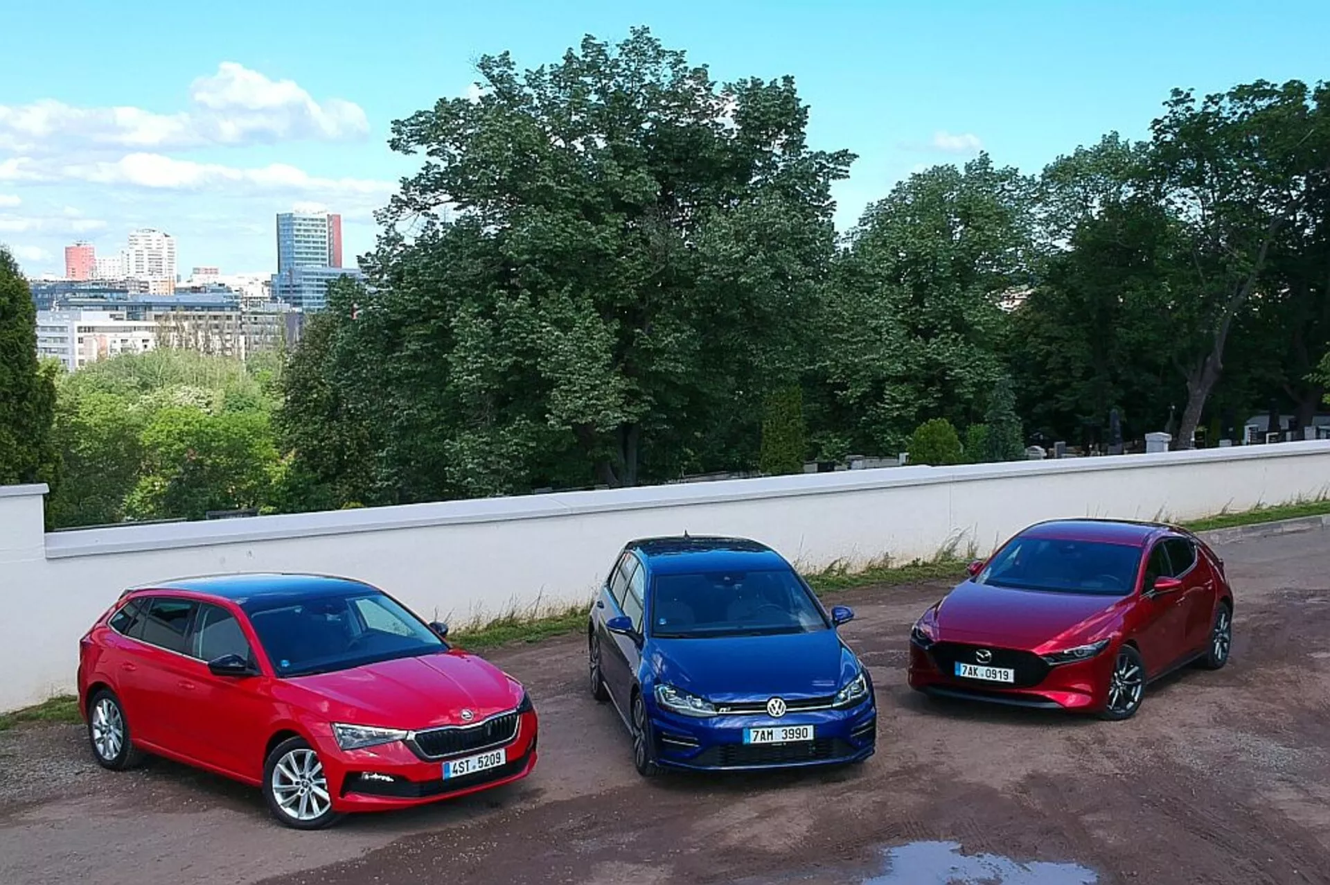 Hatchbacki Skoda Scala rocznik 2019 zaparkowane obok siebie w miejskim otoczeniu, prezentujące kolory czerwony, niebieski i burgund, z wysokim kątem ujęcia z podwyższonego stanowiska, podkreślające ich aluminiowe felgi, halogenowe reflektory i aerodynamiczne wzornictwo