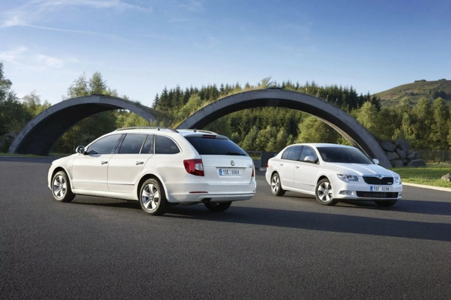 Skoda Superb kombi z 2008 roku w dzień, prezentująca tylne i przednie kąty trzech czwartych na asfaltowej drodze przeciwko zieleni i zakrzywionemu mostowi, skupiając się na elementach projektowych takich jak tylne światła, grill przedni i sylwetka pojazdu.