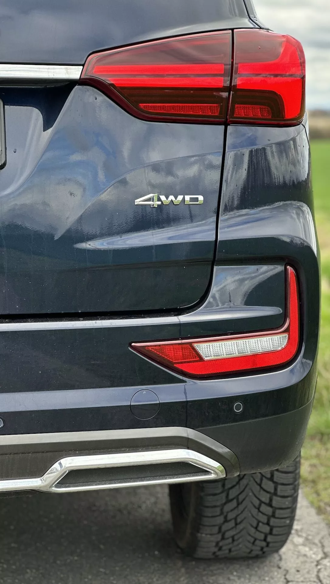 Szczegółowy widok tylnej części SsangYong Rexton 2021 przedstawiający zespół świateł tylnych LED, oznaczenie 4WD, czujnik parkowania, zintegrowaną pokrywę wydechu w metalicznym lakierze