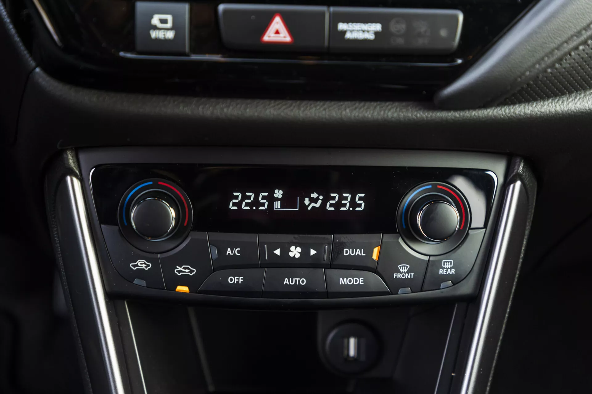 Zbliżenie na system kontroli klimatyzacji dwustrefowej Suzuki S-Cross 2022 pokazujący ustawienia temperatury, wybór trybów i opcje rozmrażania