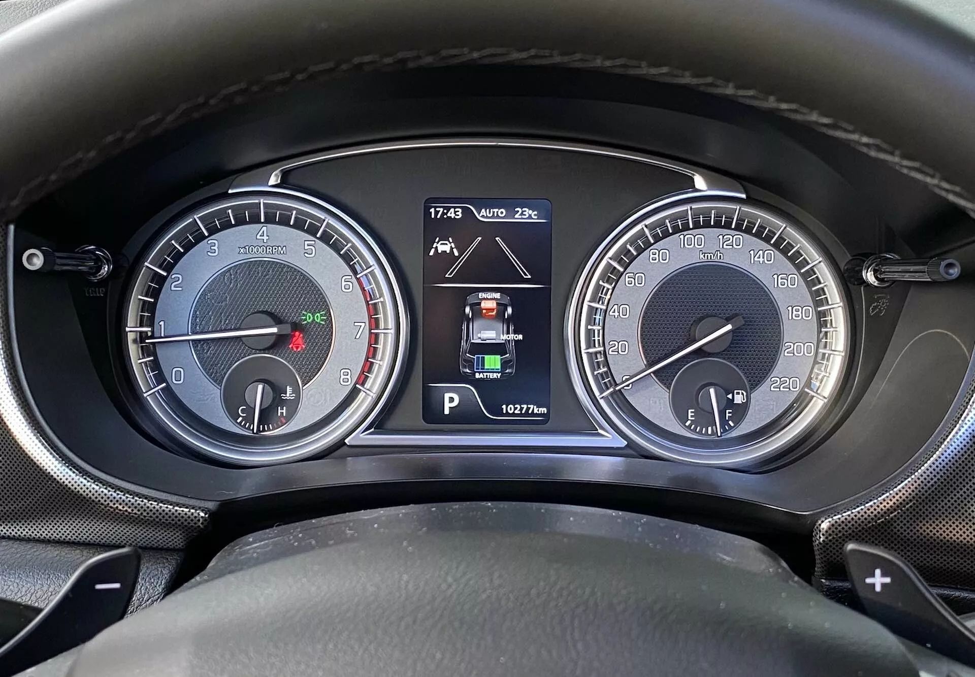 Zbliżenie tablicy rozdzielczej Suzuki Vitara 2018 z perspektywy kierowcy. Obraz przedstawia dwa analogowe wskaźniki, w tym obrotomierz (do 7000 obr./min) z małym wskaźnikiem paliwa i prędkościomierz (do 260 km/h) z małym wskaźnikiem temperatury silnika. Centralny wyświetlacz cyfrowy pokazuje tryb Park, wskaźniki wspomagania parkowania, temperaturę zewnętrzną (20°C), godzinę (17:43) i odczyt licznika przebiegu (162776 km). Oznaczenia przełączników biegów sugerują automatyczną lub półautomatyczną skrzynię biegów.