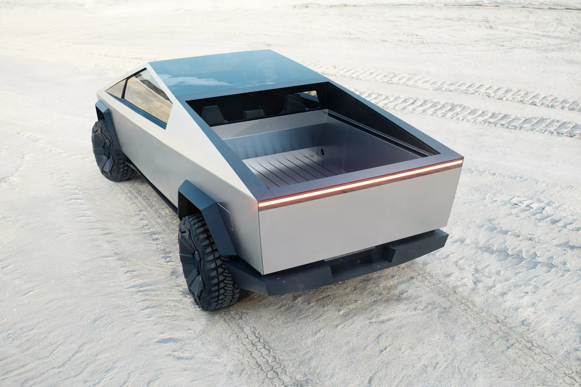 Futurystyczny i wyjątkowy Tesla Cybertruck 2021, pierwsza generacja, uchwycony z wysokiego tylnego kąta. Widok obejmuje tylną skrzynię pojazdu, część jego bocznego profilu oraz płaski dach. Tylna skrzynia jest płytka z płaską powierzchnią, podkreślona ciągłym paskiem świetlnym, podkreślającym nowoczesny design. Panele boczne nie mają konwencjonalnych stylów, pokazując minimalistyczne podejście. Duże terenowe opony sugerują zdolność do jazdy poza drogami. Brak tradycyjnych luster i wydechów sugeruje możliwe zasilanie elektryczne. Ciężarówka jest ustawiona na płaskiej, teksturowanej powierzchni przypominającej solnisko.