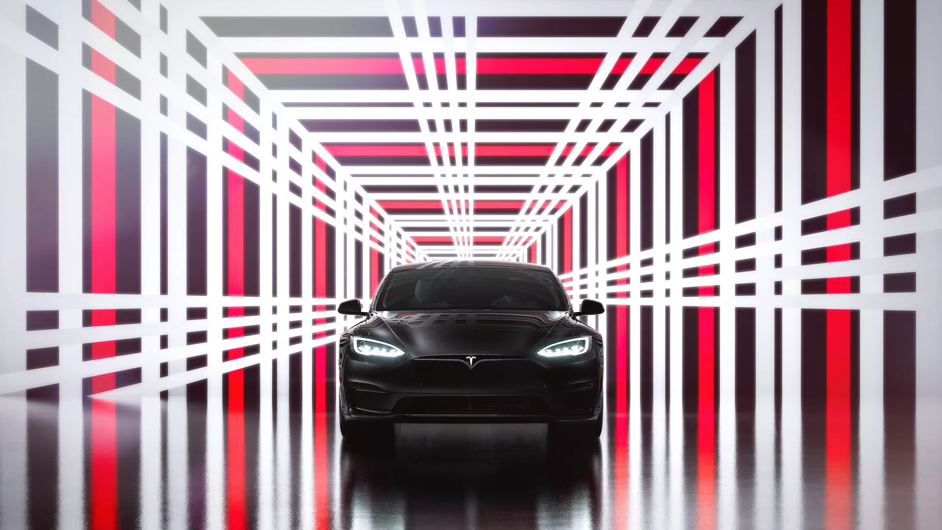 Widok z przodu Tesli Model S z 2016 roku, pierwsza generacja po liftingu. Obraz podkreśla nowoczesny, elegancki design z agresywnym przednim pasem, wyraźnie widocznym emblematem na grillu, nowoczesnymi reflektorami LED lub HID i gładkimi zarysami maski. Dolny zderzak sugeruje sportowy charakter z wlotami powietrza, podczas gdy samochód stoi na odblaskowej powierzchni w futurystycznej strukturze tunelu z jasnymi czerwonymi i białymi neonowymi światłami. Bezpośredni symetryczny widok podkreśla design i symetrię, co czyni go idealnym do prezentacji w materiałach marketingowych motoryzacyjnych.