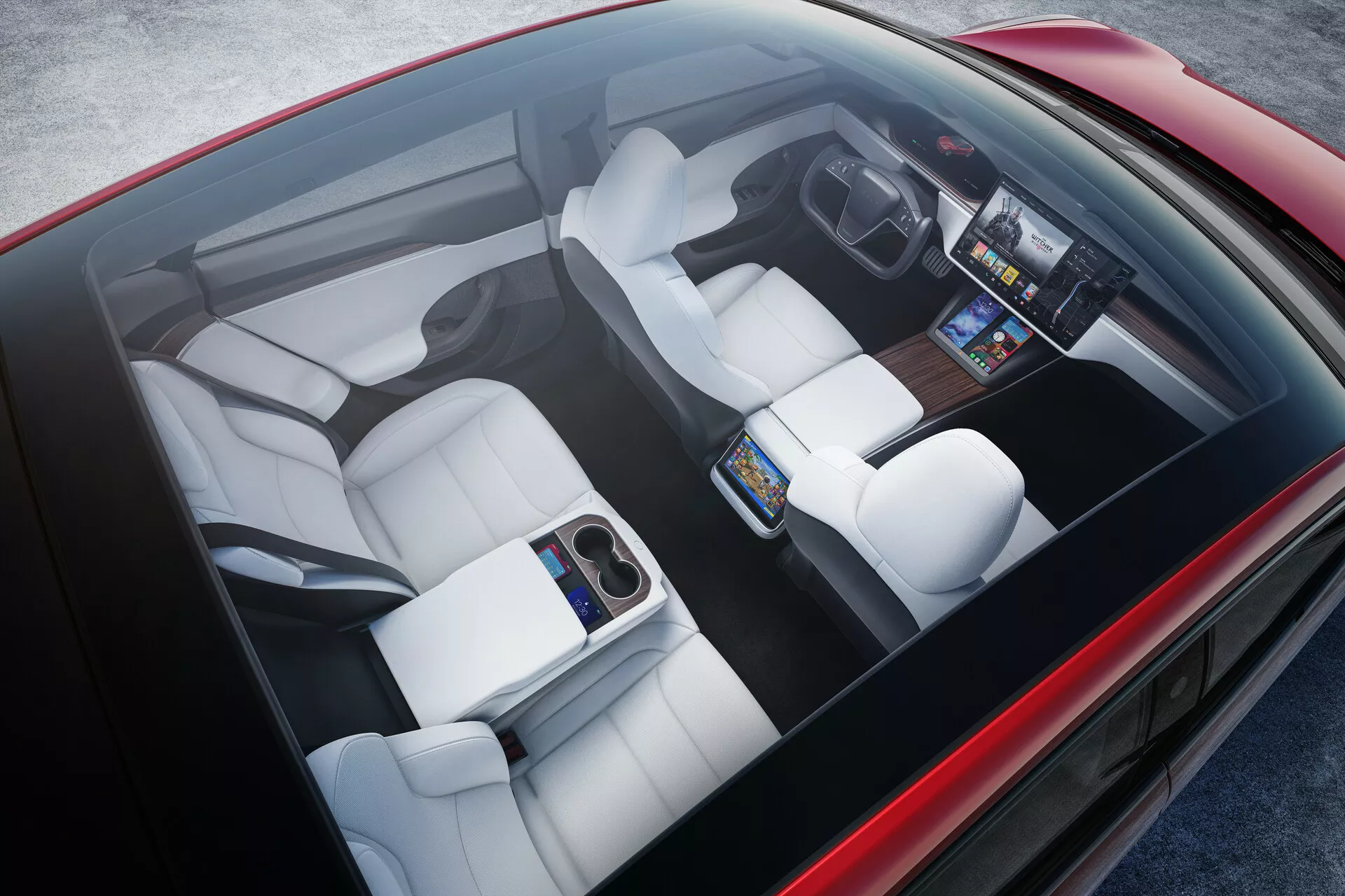 Widok z góry na wnetrze Tesli Model S 2016 (1. generacja, facelift). Wnętrze wyposażone w białe tapicerowane siedzenia z indywidualnymi konturami, centralny duży ekran dotykowy na przedniej desce rozdzielczej, cyfrowy zestaw wskaźników, minimalistyczną konsolę środkowa i składany podłokietnik z tyłu. Wskazuje na zaawansowaną technologię, ergonomiczny design i nowoczesny luksus.
