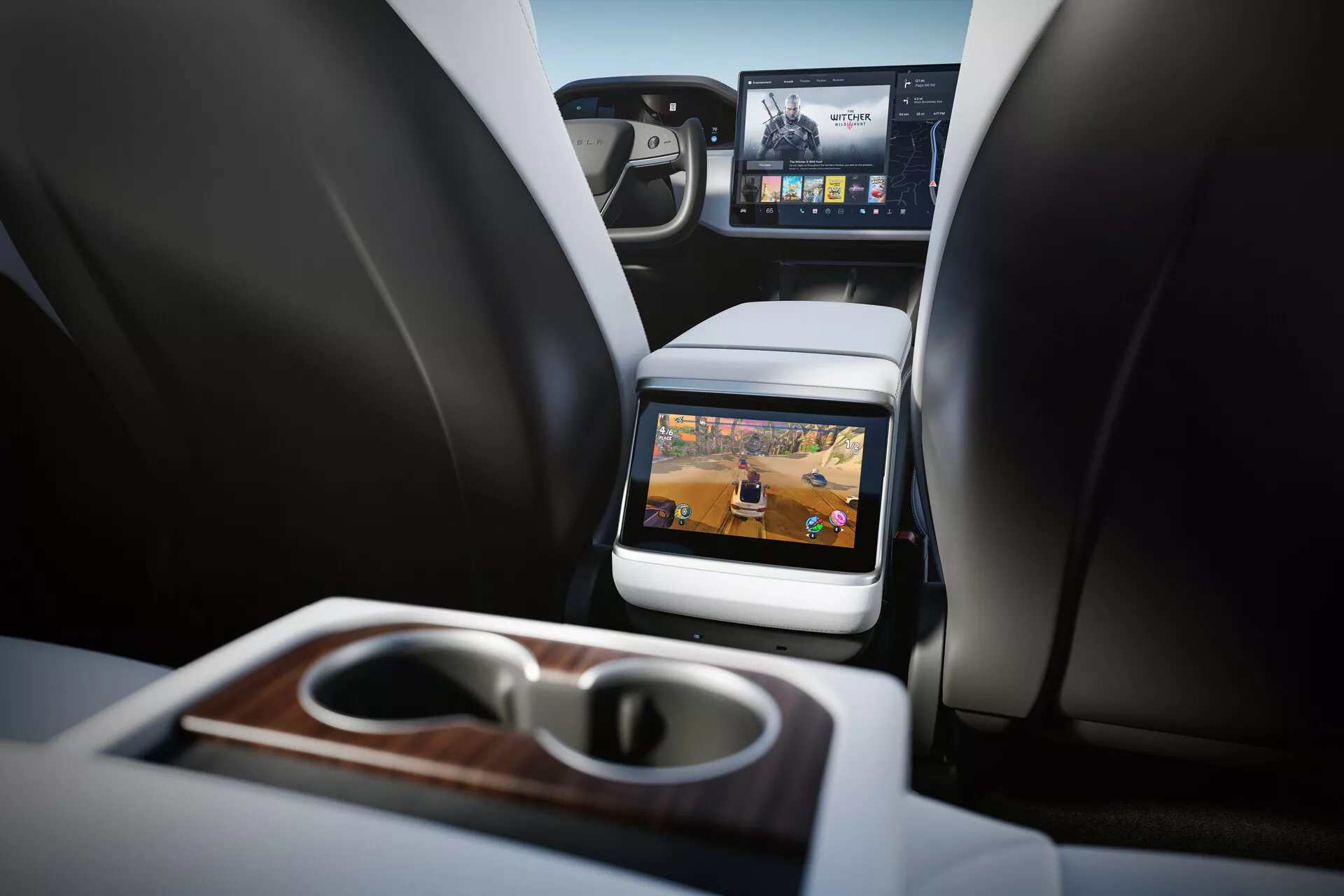 Widok wnętrza Tesla Model S 2016 (pierwsza generacja facelift) skupiający się na tylnym przedziale pasażerskim. Perspektywa od strony tylnego siedzenia na wysokości poduszki, widoczne dwa przednie siedzenia z zagłówkami, konsola środkowa i wbudowany ekran na tylnej stronie siedzenia pasażera. Technologia rozrywki dla tylnych pasażerów widoczna jest z aktywnym ekranem wyświetlającym multimedialne treści. Funkcje obejmują składany podłokietnik z wbudowanymi uchwytami na kubki i drewnianym wykończeniem, częściowy widok tablicy rozdzielczej z większym ekranem infotainment oraz luksusowe materiały. Wnętrze dobrze oświetlone z neutralnymi tonami, wskazujące na nowoczesny luksusowy pojazd.