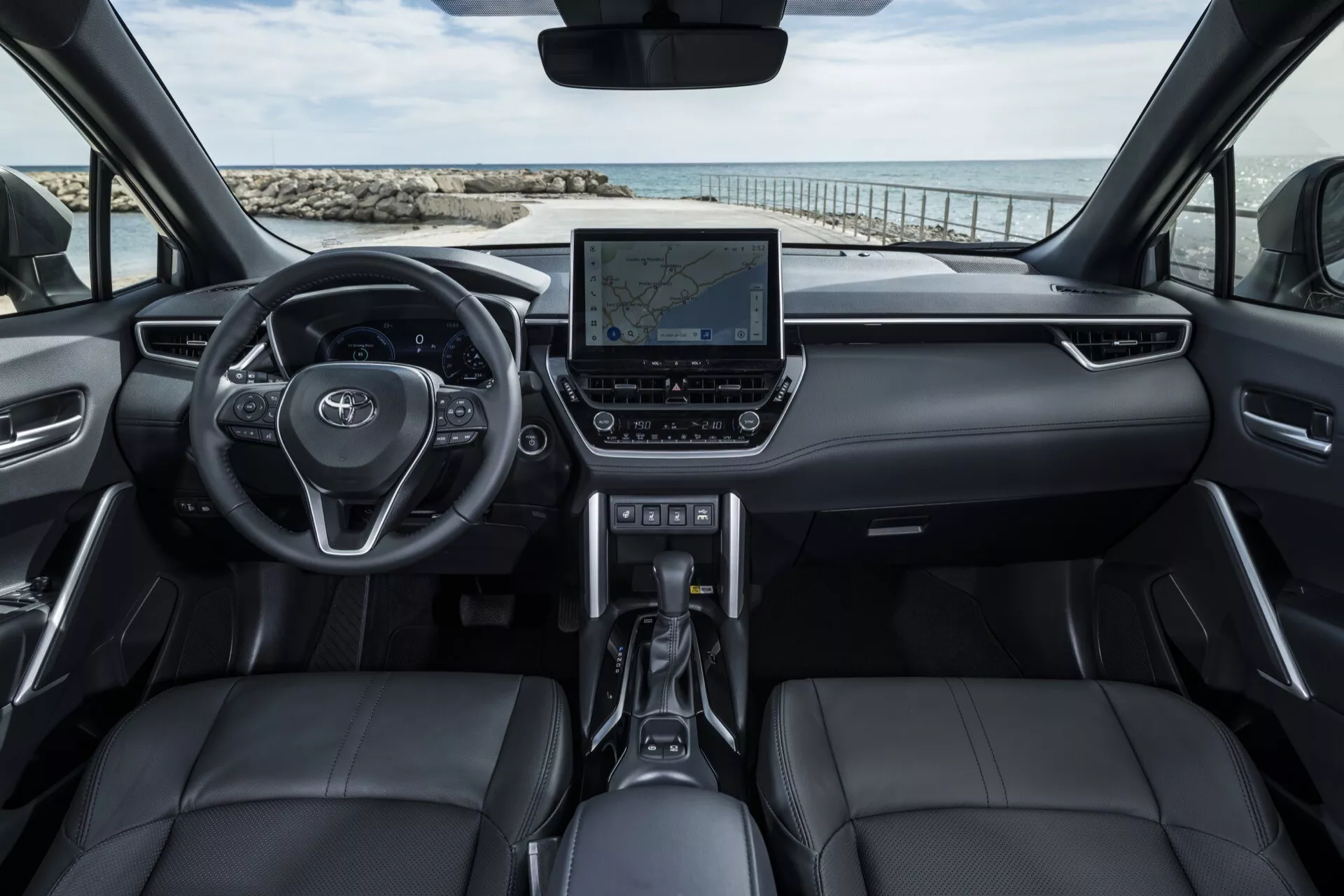 Wnętrze Toyoty Corolla Cross 1. generacji z 2022 r., pokazujące wielofunkcyjną kierownicę, cyfrowy wyświetlacz deski rozdzielczej, czarne skórzane siedzenia i zaawansowany system informacyjno-rozrywkowy