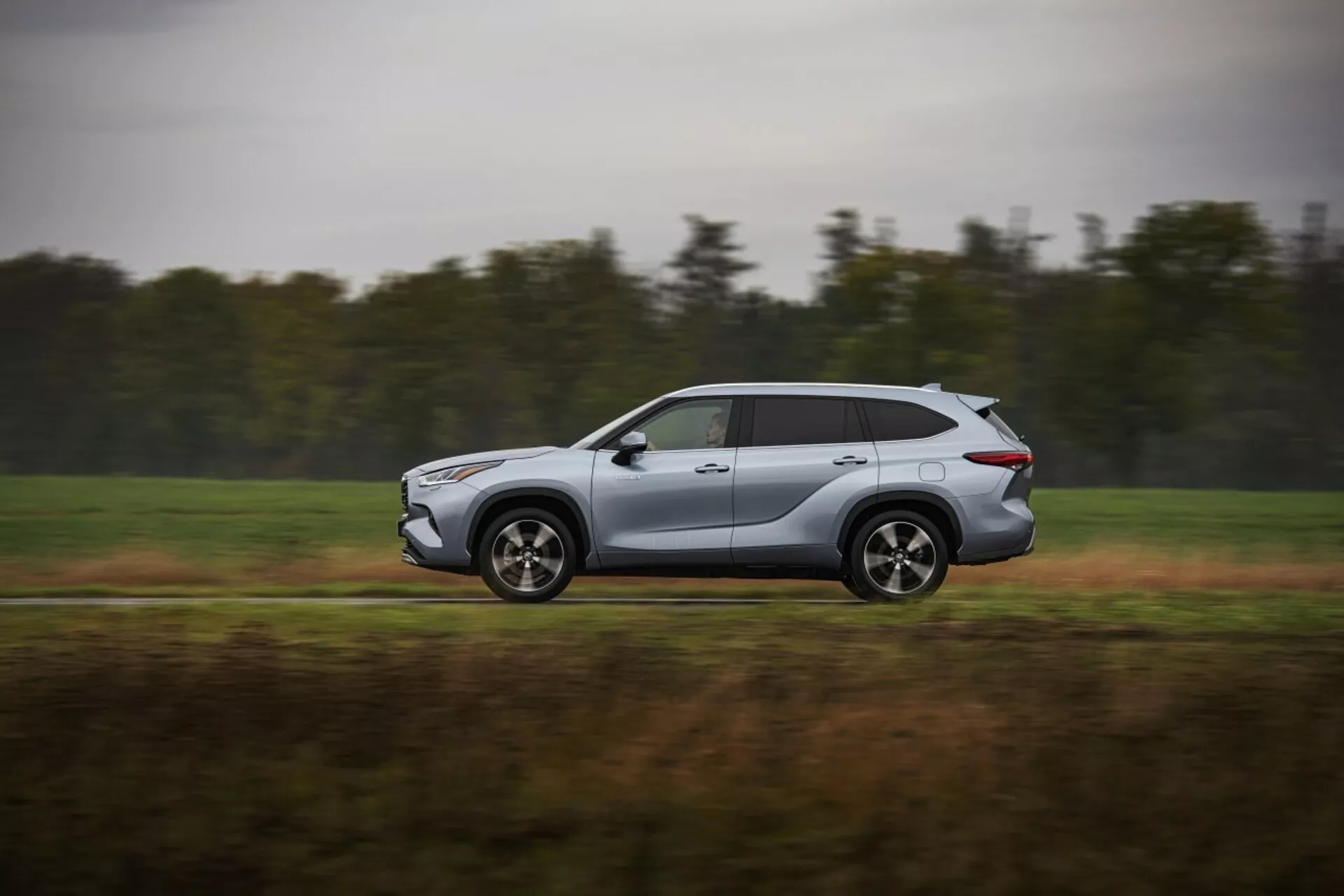 Toyota Highlander 2021 w ruchu, nowoczesne srebrne SUV uchwycone z profilu bocznego, prezentujące aerodynamiczny design i funkcje technologiczne