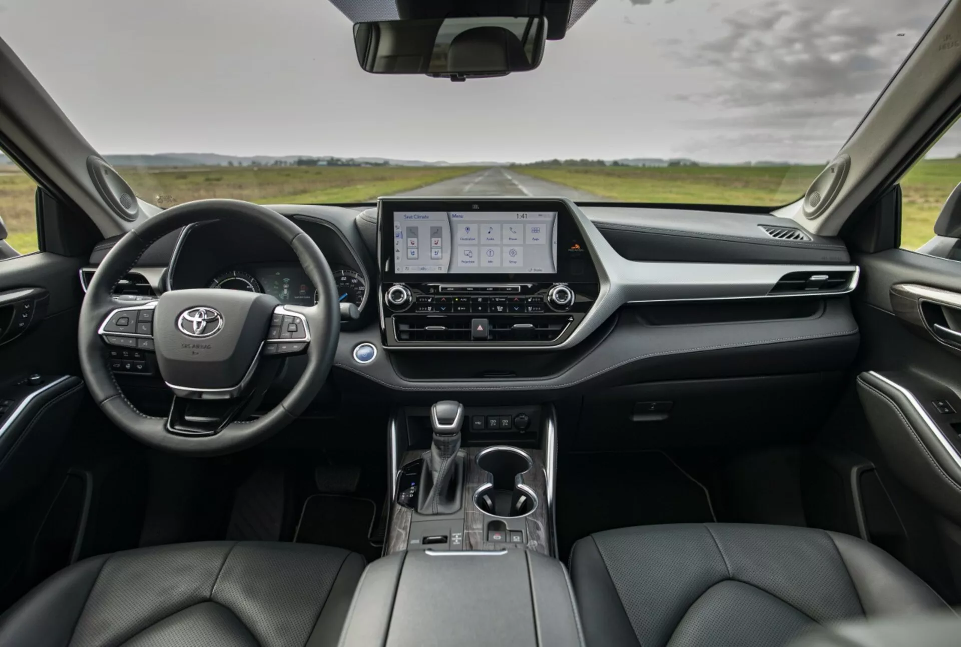 Przegląd wnętrza Toyoty Highlander 2021 ukazujący deski rozdzielczej, cyfrowy zespół wskaźników, wyświetlacz systemu multimedialnego i fotele przednie z tapicerką skórzaną z perspektywy tylnych siedzeń