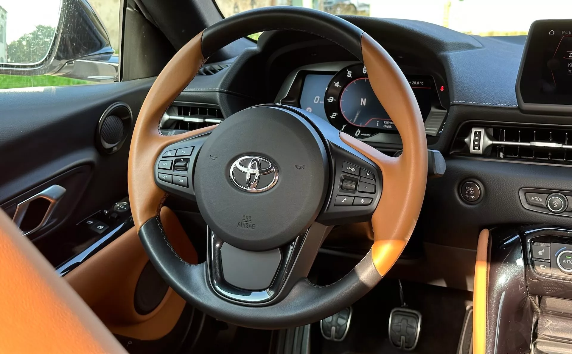 Widok wnętrza Toyota Supra (GR-Supra) 2019 z perspektywy kierowcy z detalicznie zaprojektowaną kierownicą zawierającą sterowanie multimediów i informacji o pojeździe, cyfrowy panel zegarów i zaawansowany system rozrywki