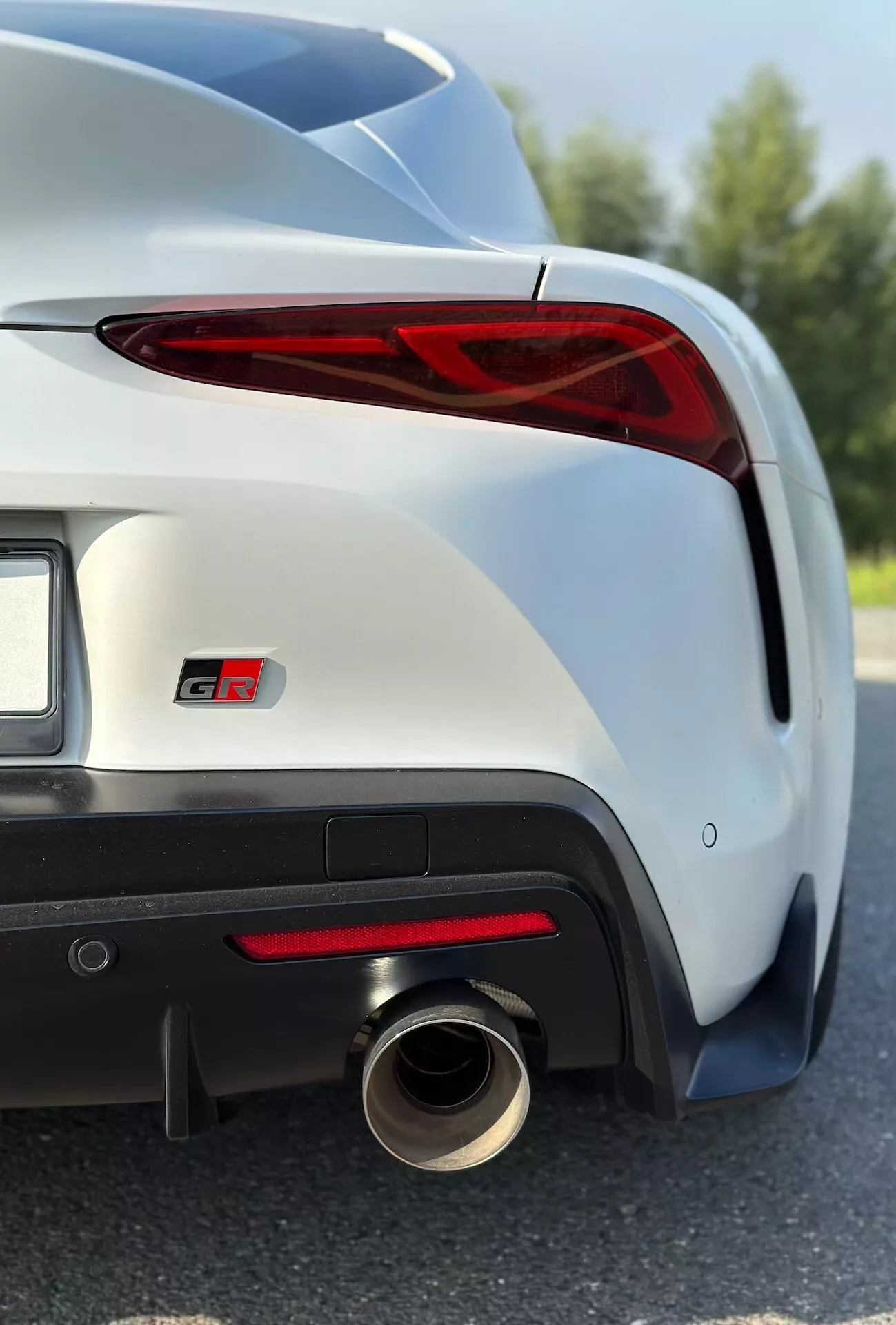 Szczegółowy widok Toyoty Supra GR 2019 z akcentem na prawym tylnym świetle LED, emblemacie GT, sportowym zderzaku tylnym i układzie wydechowym w metalicznym wykończeniu