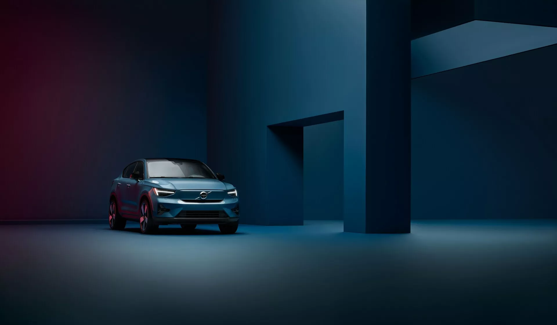 Profesjonalna fotografia Volvo C40 z 2021 roku (1. generacja) z przedniego widoku trzech czwartych, podkreślająca nowoczesną kratkę, reflektory LED i smukły profil boczny w słabo oświetlonym, nastrojowym studio.
