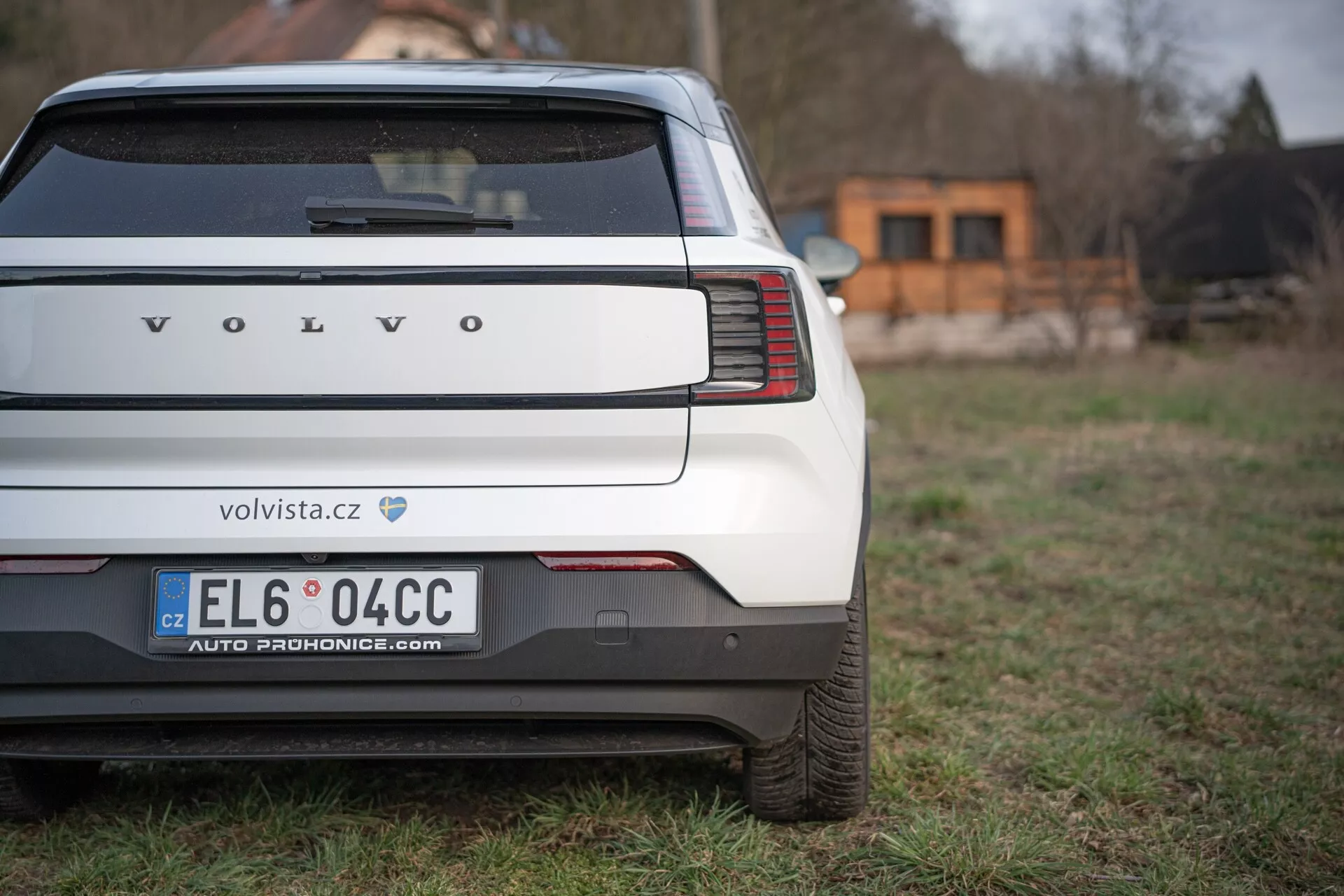 Tylny widok Volvo EX30 2024 podkreślający unikatowe pionowe światła tylne, tylny zderzak i obszar tablicy rejestracyjnej na trawiastym tle