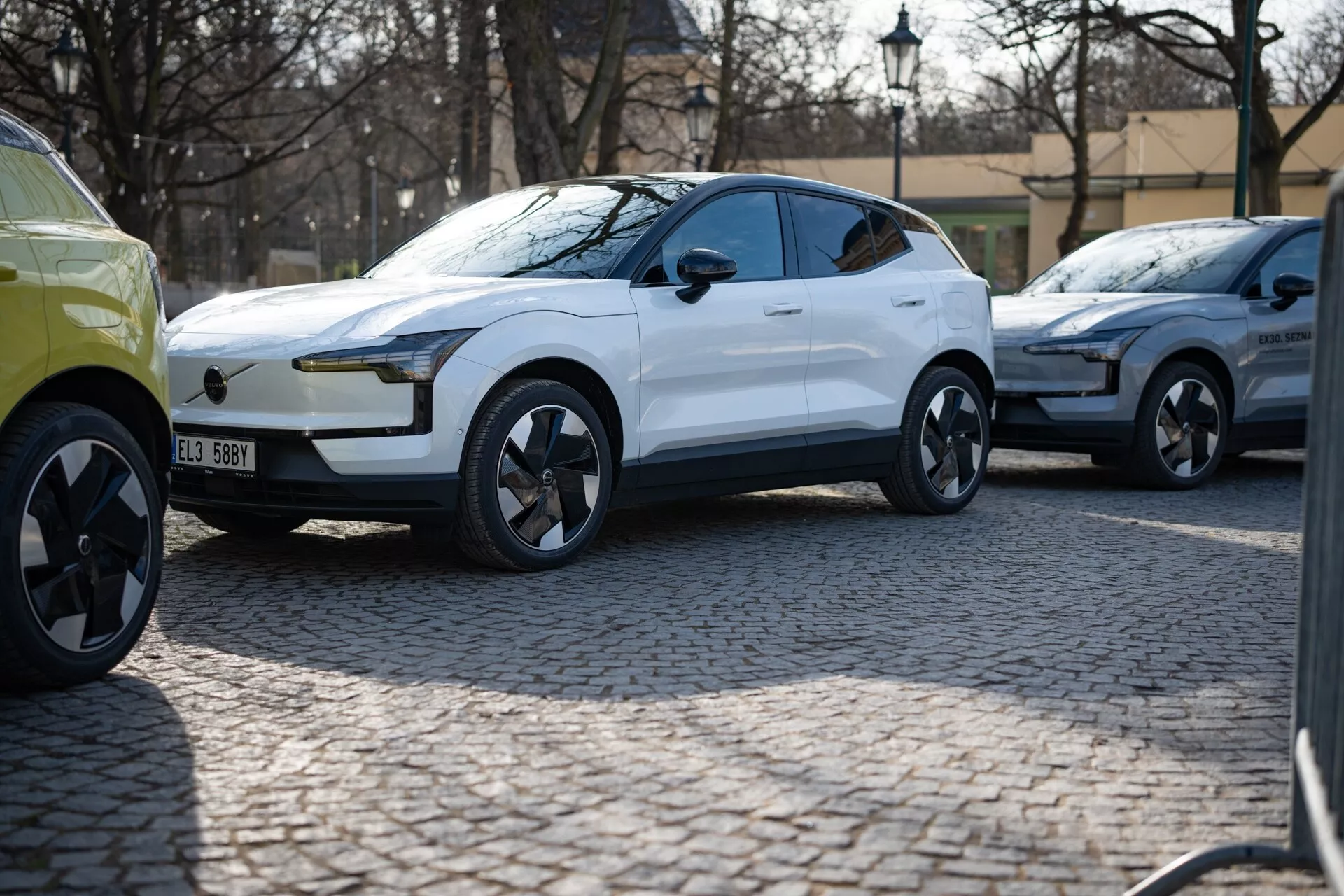 Biały, nowoczesny SUV crossover z 2024 roku w widoku z trzech czwartych parkujący na brukowanej ulicy, z błyszczącym lakierem, diodami LED do jazdy dziennej, klamkami drzwi wpuszczanymi w nadwozie i dynamicznie zaprojektowanymi kołami ze stopów sugerującymi luksus i wydajność, prawdopodobnie pojazd elektryczny.