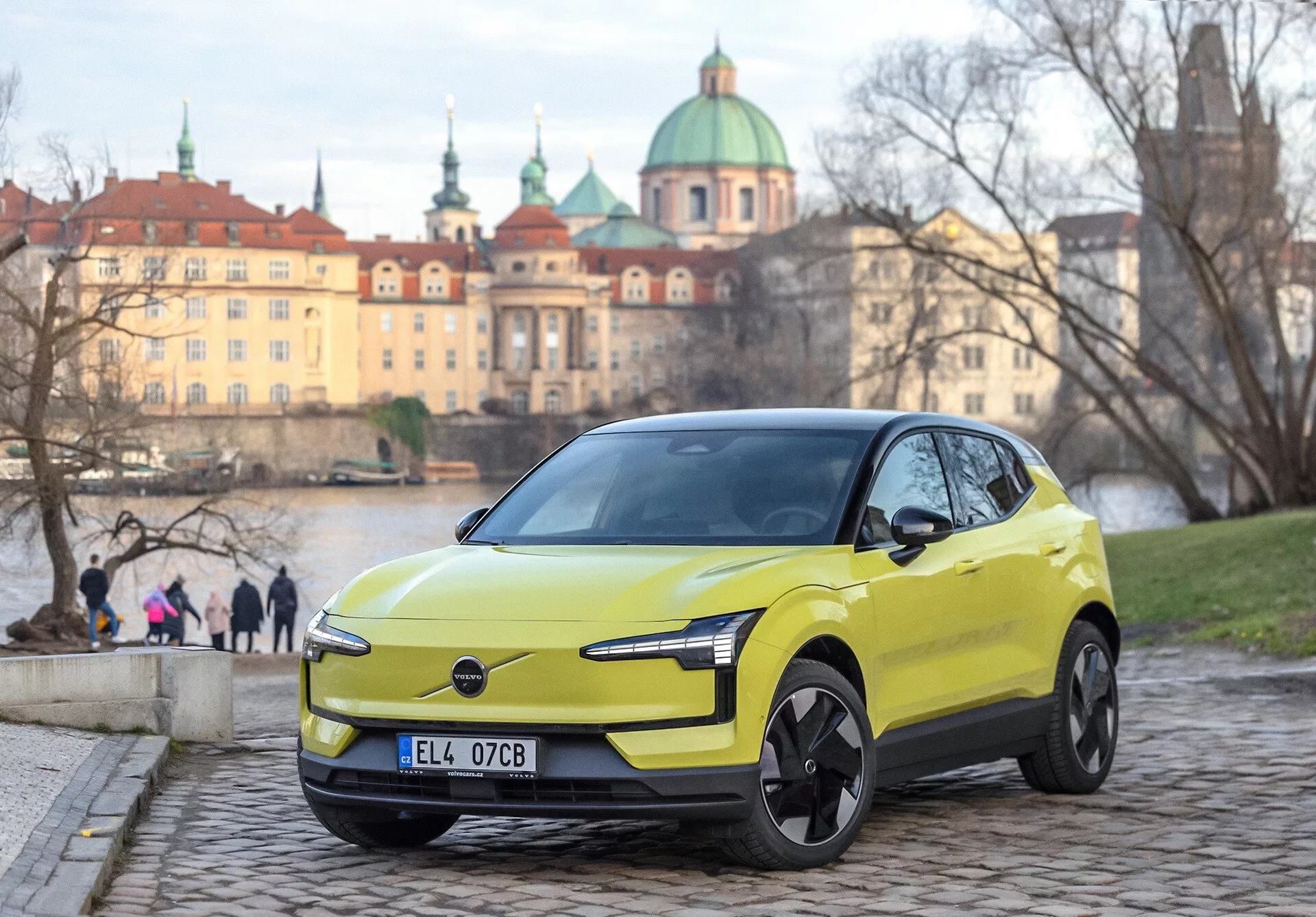 Volvo EX30 2024 w kolorze limonkowym, widok z przodu pod kątem trzy czwarte na kostce brukowej, z nowoczesnymi reflektorami LED i cechami designu elektrycznego, europejskie tło miejskie