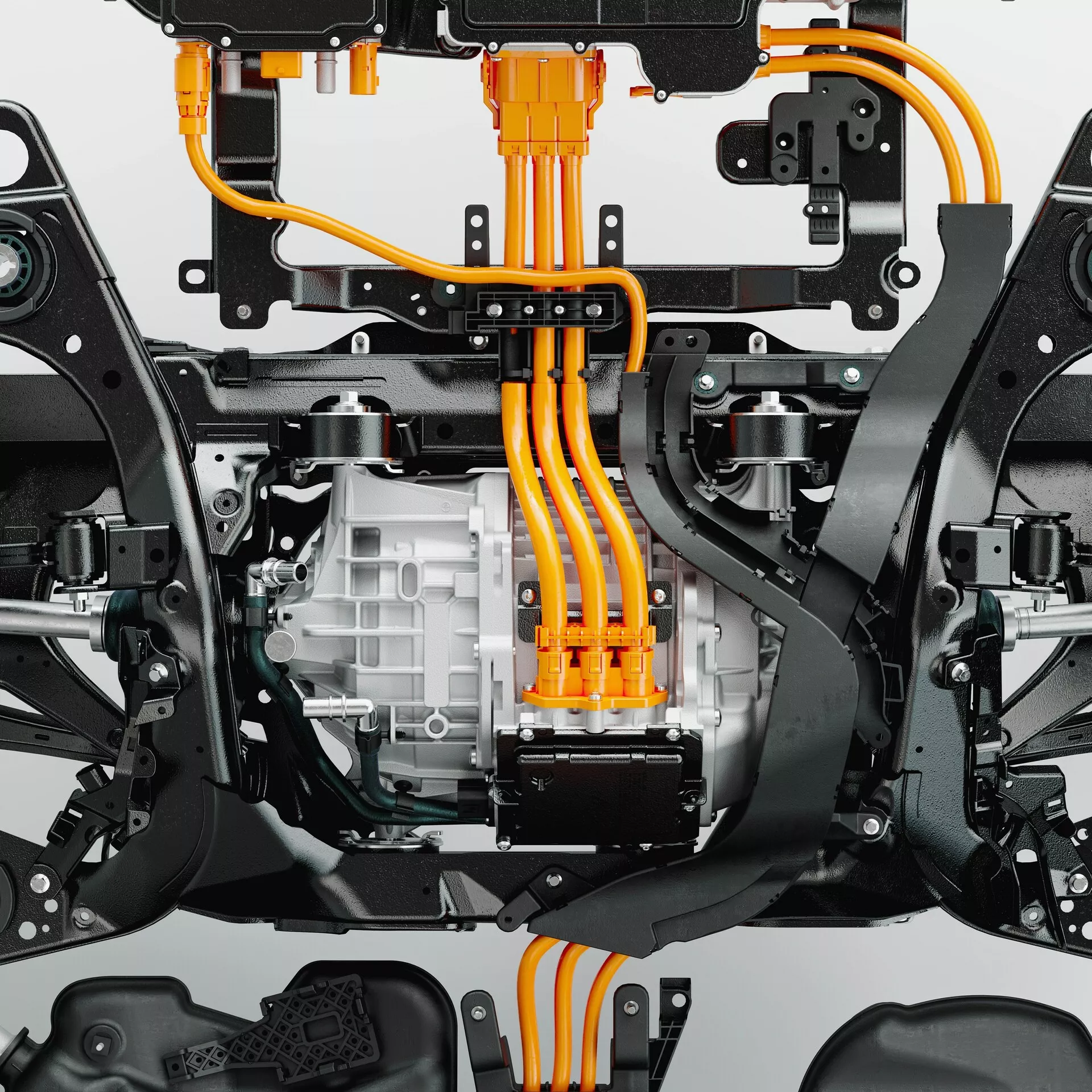Zbliżenie dolnej części Volvo XC60 2021 (lifting 2. generacji), podkreślające elementy elektrycznego układu napędowego i podwozia. Zdjęcie zrobione z kąta od dołu przedstawia dużą obudowę silnika elektrycznego z żeberkami chłodzącymi na środku, jasnopomarańczowe kable wysokiego napięcia oraz komponenty zawieszenia, takie jak wahacze. Ułożenie kabli sugeruje połączenie z centralnie umieszczonym pakietem akumulatorów. Widoczne części podwozia i ramy zapewniają punkty montażowe dla układu napędowego i zawieszenia, prezentując zaawansowane napędy elektryczne oraz systemy elektryczne wysokiego napięcia.