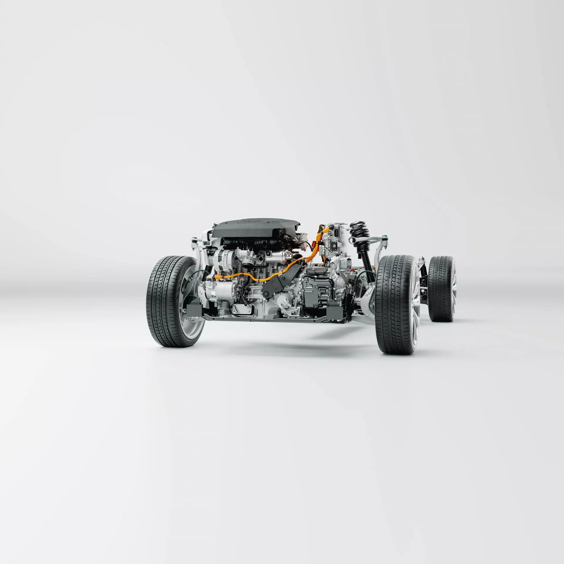 Chassis Volvo XC60 2021 drugiej generacji po liftingu bez nadwozia jest pokazane w perspektywie przedniego trzy czwarte. Obraz pokazuje szczegółowe widoki niezależnego układu zawieszenia, amortyzatorów, tarcz hamulcowych i zacisków, ramy podwozia, subramy, silnika, skrzyni biegów i pomarańczowych kabli technologii elektrycznej lub hybrydowej. Fotografowane na czystym, białym tle, to zdjęcie podkreśla mechaniczne komponenty i symetrię inżynieryjną pojazdu.