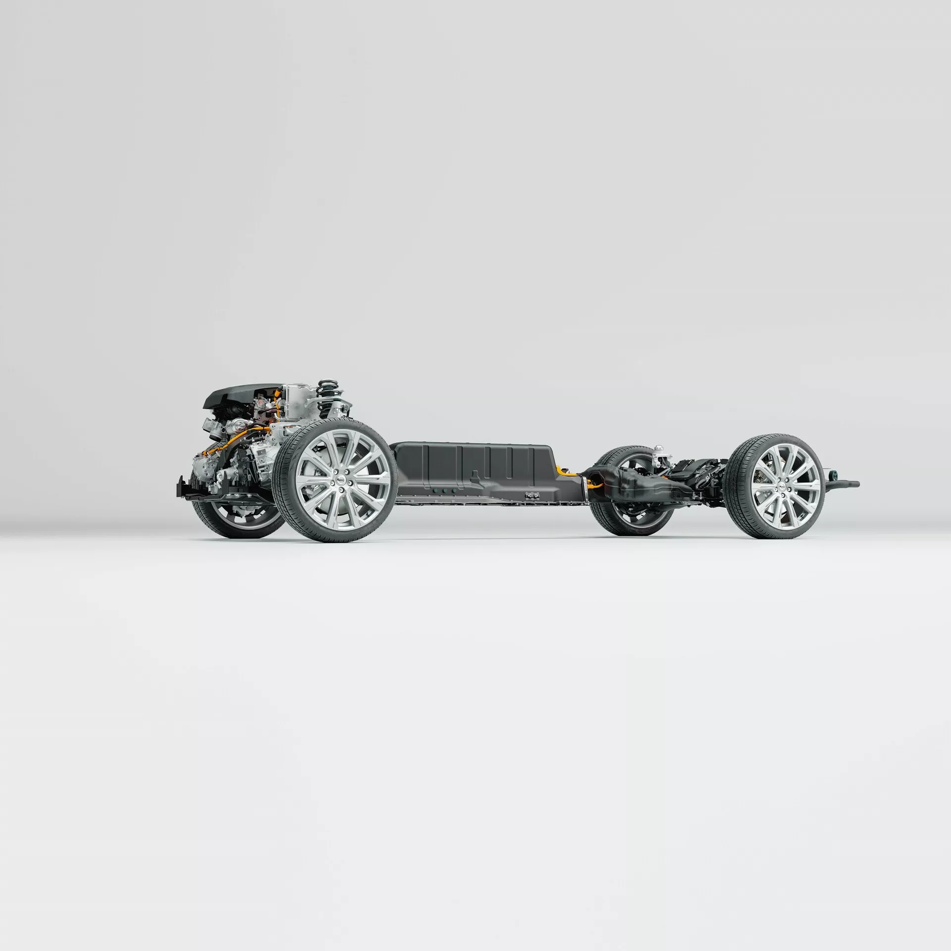 Widok bocznego profilu podwozia Volvo XC60 2021 (druga generacja-po liftingu). Obraz podkreśla ramę pojazdu, koła z nowoczesnymi alufelgami, komponenty zawieszenia, przedni układ napędowy i centralny pakiet baterii, wszystko na czystym, neutralnym tle. Zdjęcie ujawnia skomplikowane szczegóły zaawansowanej inżynierii bez karoserii ani komponentów wewnętrznych.