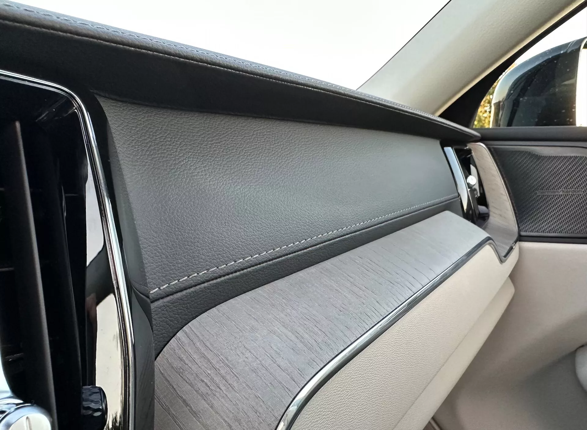 Zbliżenie na panel drzwi wewnętrznych Volvo XC60 2021 Recharge Plug-In Hybrid, podkreślające luksusowe materiały i elementy projektowe z perspektywy pasażera.