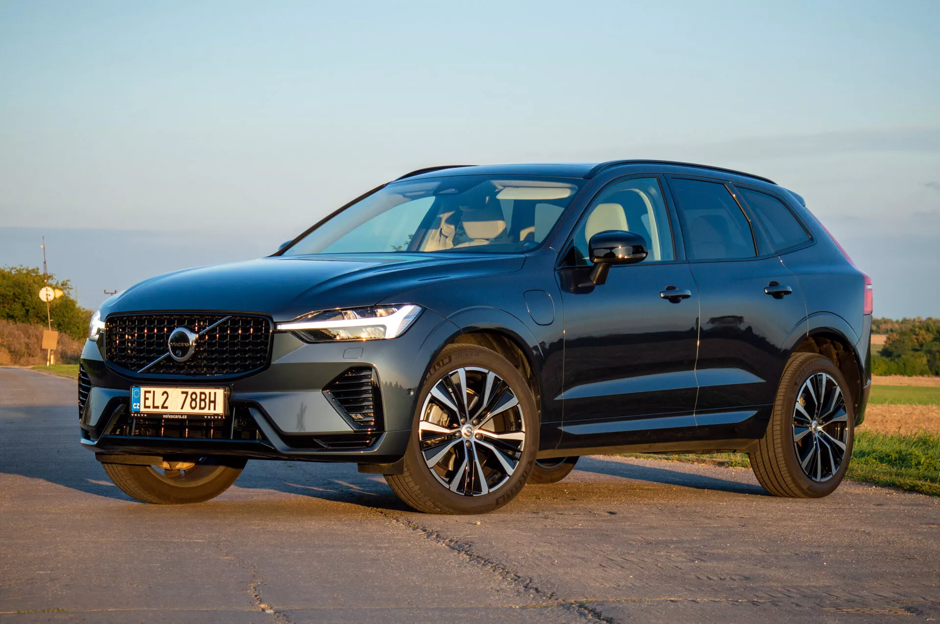SUV Volvo XC60 Recharge Plug-In Hybrid 2021 w perspektywie przedniej trzy czwarte pokazujący reflektory LED, elegancką kratę i nowoczesne felgi aluminiowe pod naturalnym światłem dziennym