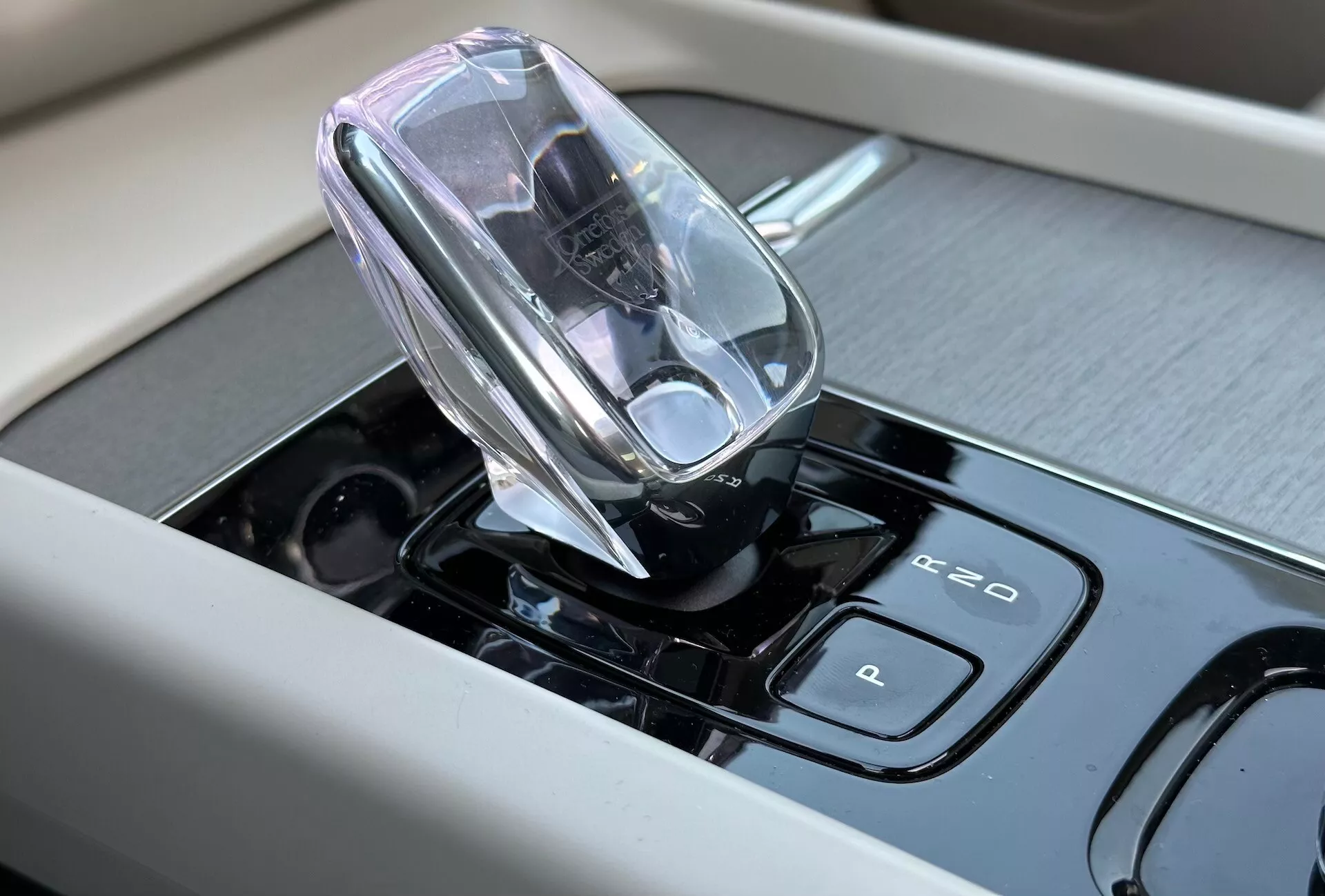Zbliżenie wnętrza Volvo XC60 Recharge Plug-in Hybrid 2021 skupione na nowoczesnej elektronicznej dźwigni zmiany biegów i panelu dotykowym