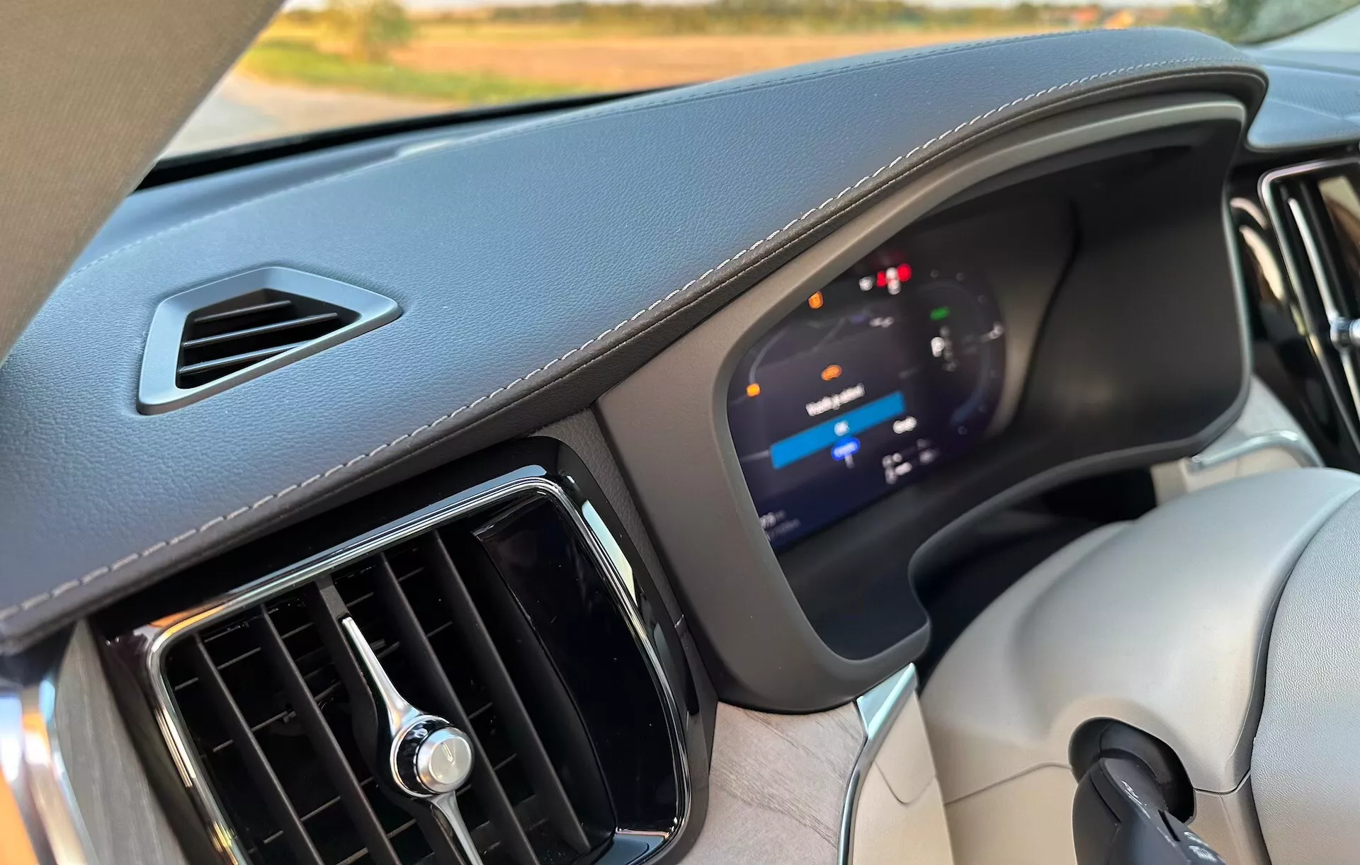 Widok wnętrza Volvo XC60 Recharge Plug-In Hybrid 2021, prezentujący deskę rozdzielczą ze skupieniem na zaawansowanym cyfrowym zespole wskaźników i materiałach wysokiej jakości, z perspektywy fotela pasażera przedniego.