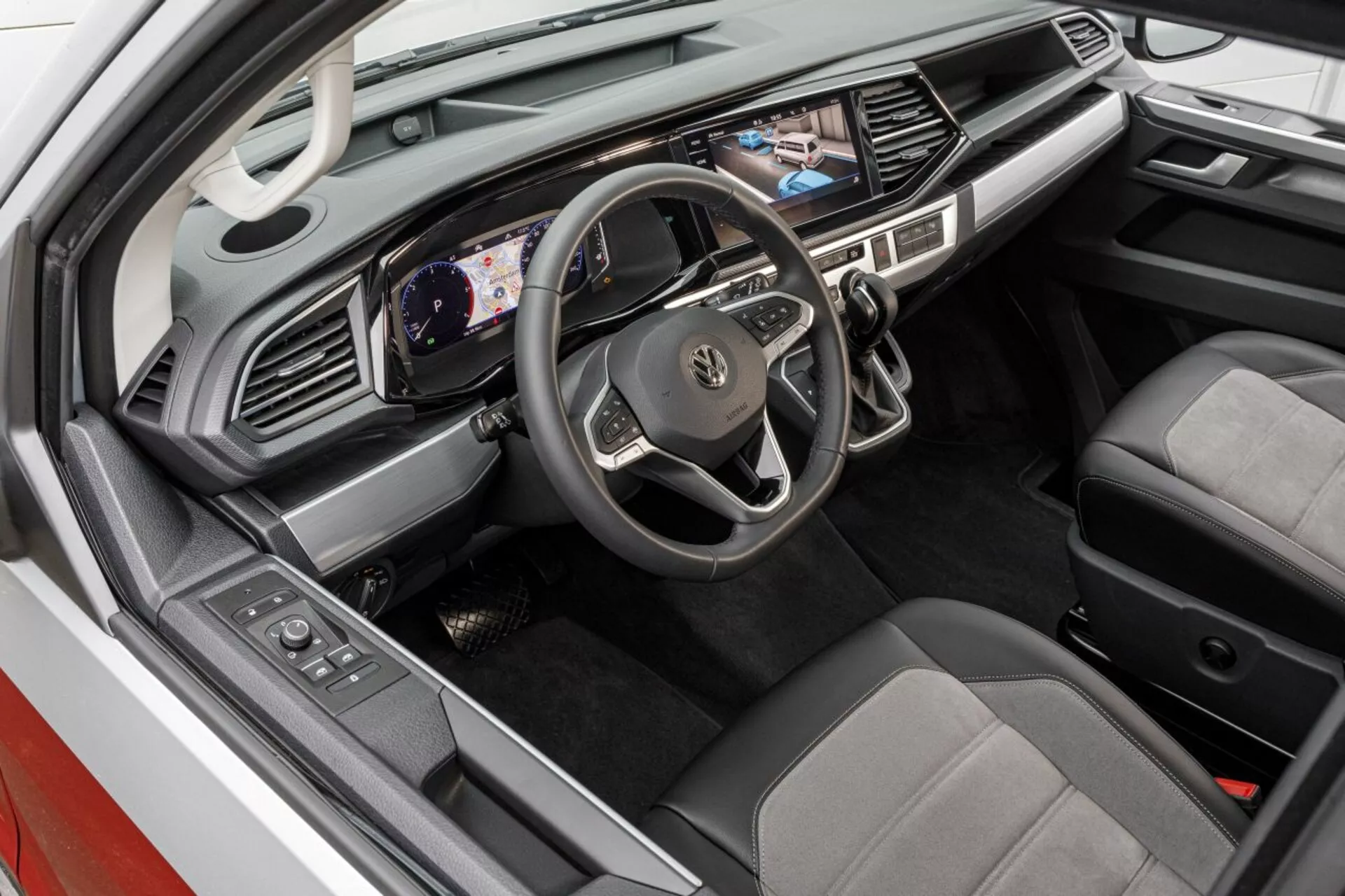 Podwyższony widok na wnętrze Volkswagen Nutzfahrzeuge Transporter 2019 (T6.1 California) ukazujący obszar kierowcy z cyfrowym kokpitem, ekranem dotykowym multimedialnym i siedzeniami w dwóch kolorach