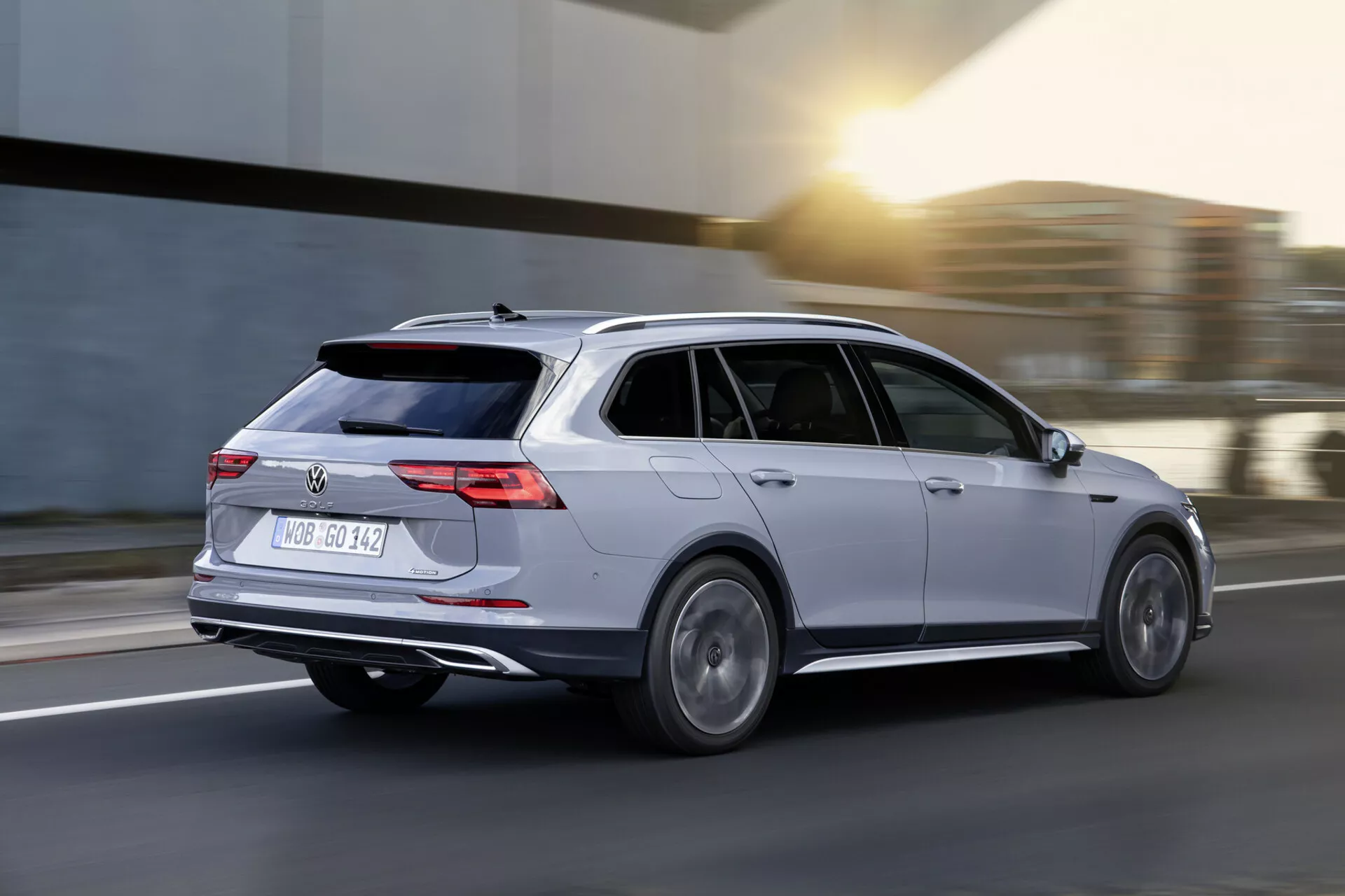 Kombi Volkswagen Golf Alltrack 2017 w ruchu, uchwycone w dynamicznym widoku z tyłu trzy czwarte ukazujące srebrną karoserię, tylne światła LED, felgi aluminiowe i aerodynamiczny design na rozmytym tle drogi.