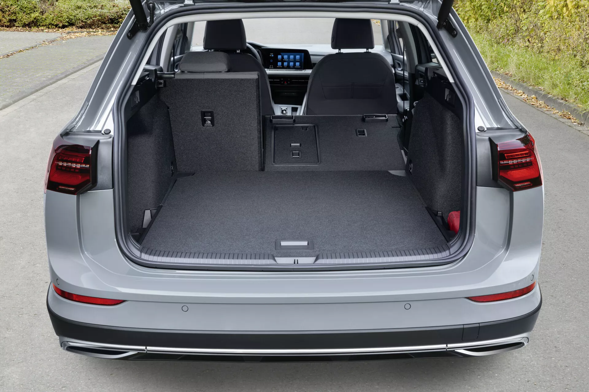 Tylna część VW Golf Alltrack 2017 widziana z podniesionego kąta, pokazująca otwarte tylne drzwi bagażnika i przestronną, dobrze oświetloną przestrzeń ładunkową z wglądem w zaawansowaną technologię tylnej kabiny