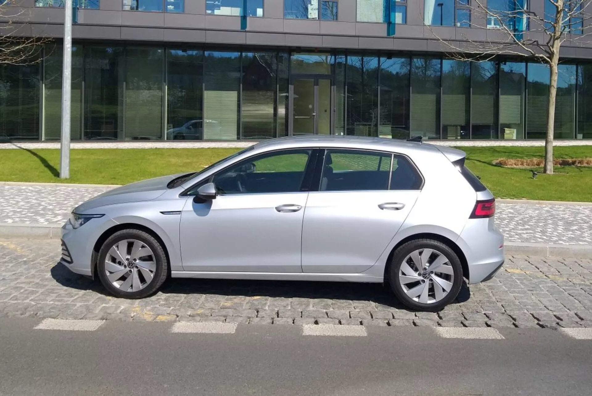 Srebrny hatchback VW Golf GTD z 2017 roku zaparkowany na utwardzonej nawierzchni w ciągu dnia przy bezchmurnym niebie, ukazujący boczny profil z aluminiowymi kołami i wyraźnymi liniami nadwozia