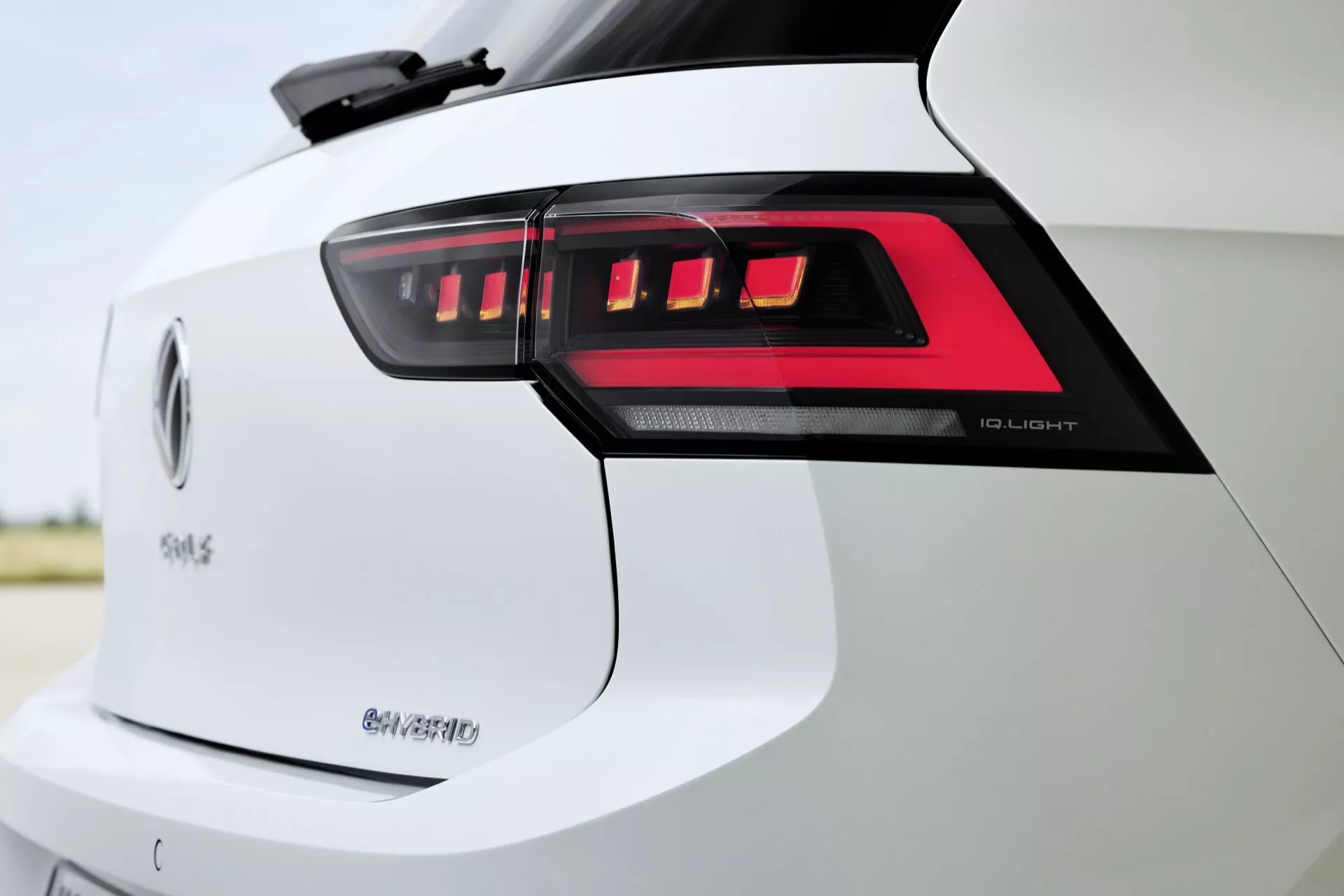 Zbliżenie na sekcję tylną VW Golf 2024 (VIII-facelift) prezentujące tylne światła LED, emblematy '50 e-tron' i 'Q4', podkreślające zaawansowaną technologię oświetlenia LED, mobilność elektryczną i potencjalne zdolności napędu na wszystkie koła w białym wykończeniu.