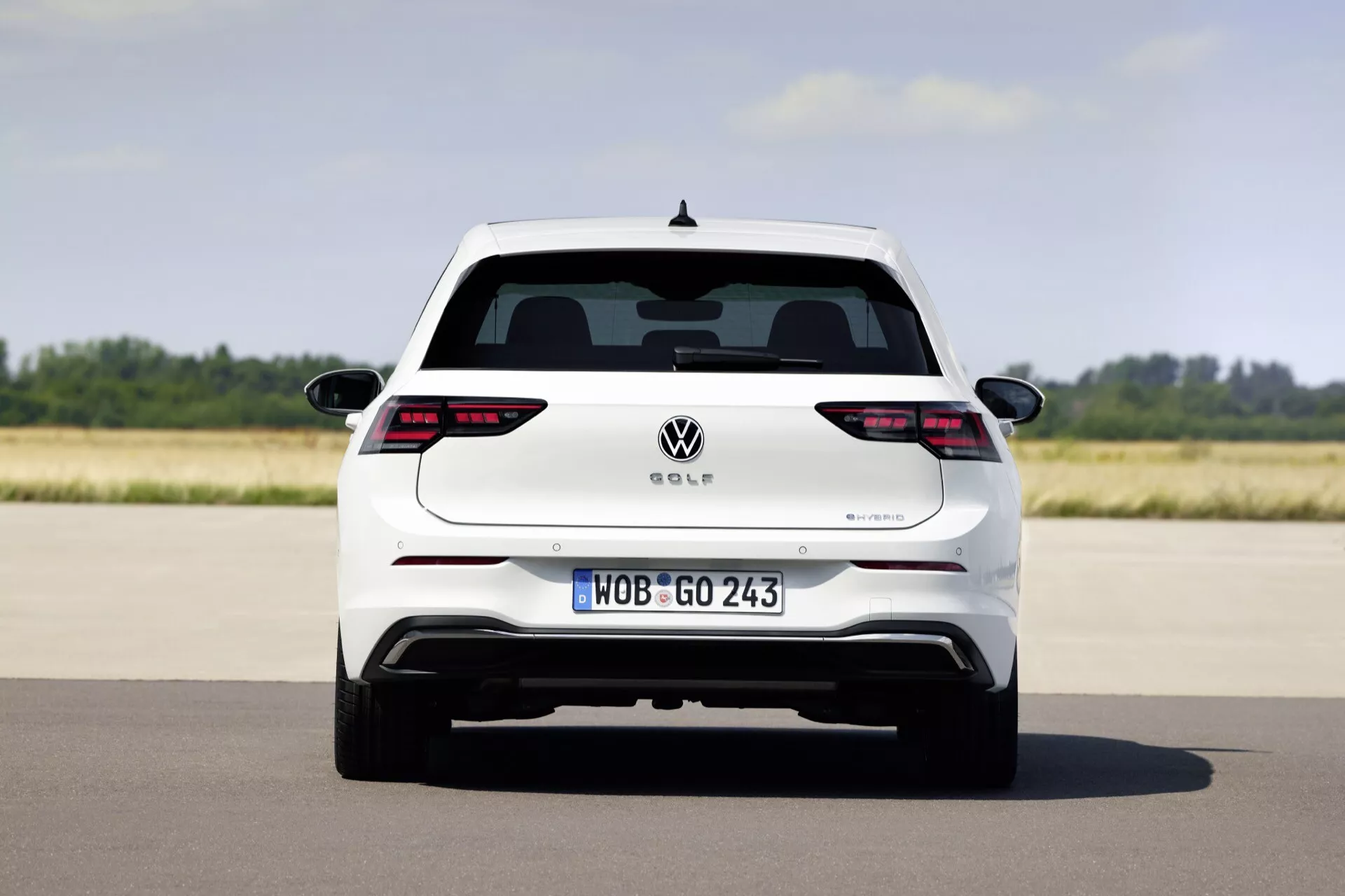 Widok z tyłu Volkswagen Golf VIII facelift 2024, pokazujący pełną szerokość i elementy projektu, takie jak światła tylne LED, europejska tablica rejestracyjna i potencjalny hybrydowy system wydechowy na otwartej drodze.