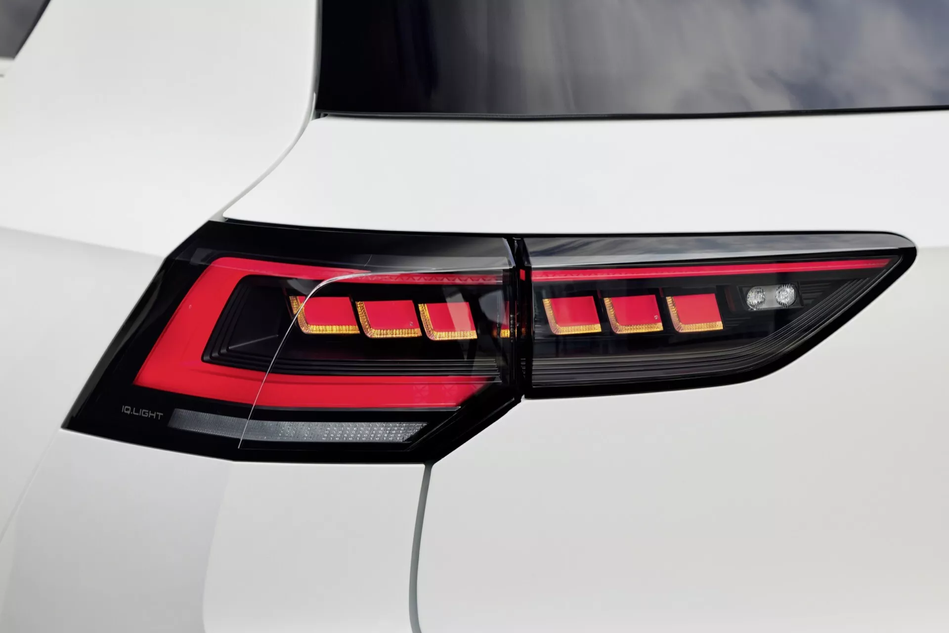 Zbliżenie na prawe tylne światło VW Golf VIII facelifting 2024 z poziomymi segmentami LED i technologią OLED na białym pojeździe