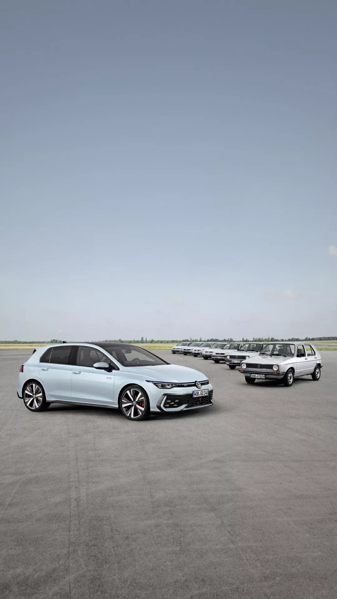 Widok z przodu i z boku na VW Golf VIII po liftingu 2024 na otwartym parkingu, podkreślający elementy projektowe takie jak reflektory LED, felgi aluminiowe i zaawansowane funkcje bezpieczeństwa, z szeregiem samochodów w tle pod bezchmurnym niebem.
