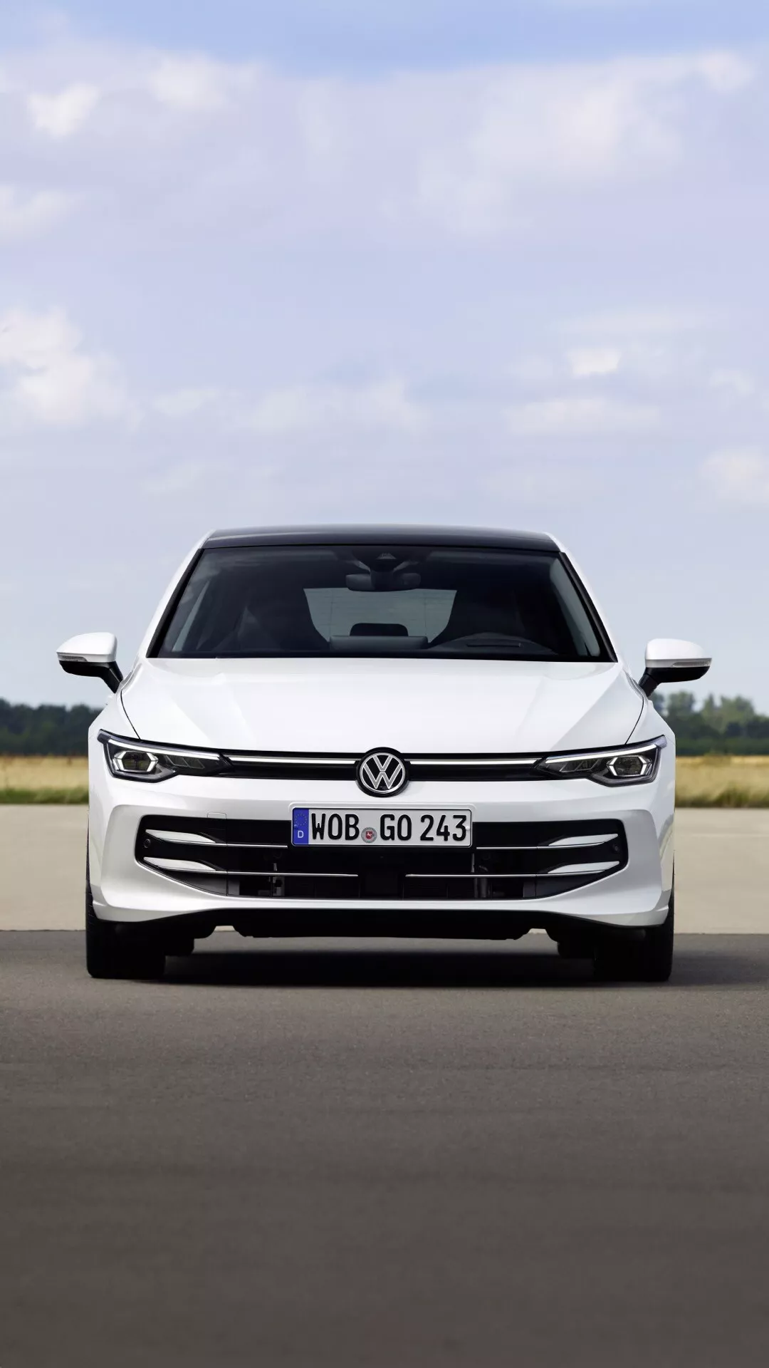 Przedni widok VW Golf (VIII Facelift) 2024 na utwardzonej nawierzchni ukazujący jego grill, eleganckie reflektory LED, emblemat i aerodynamiczny design maski, co sugeruje nowoczesną technologię i sportową estetykę.