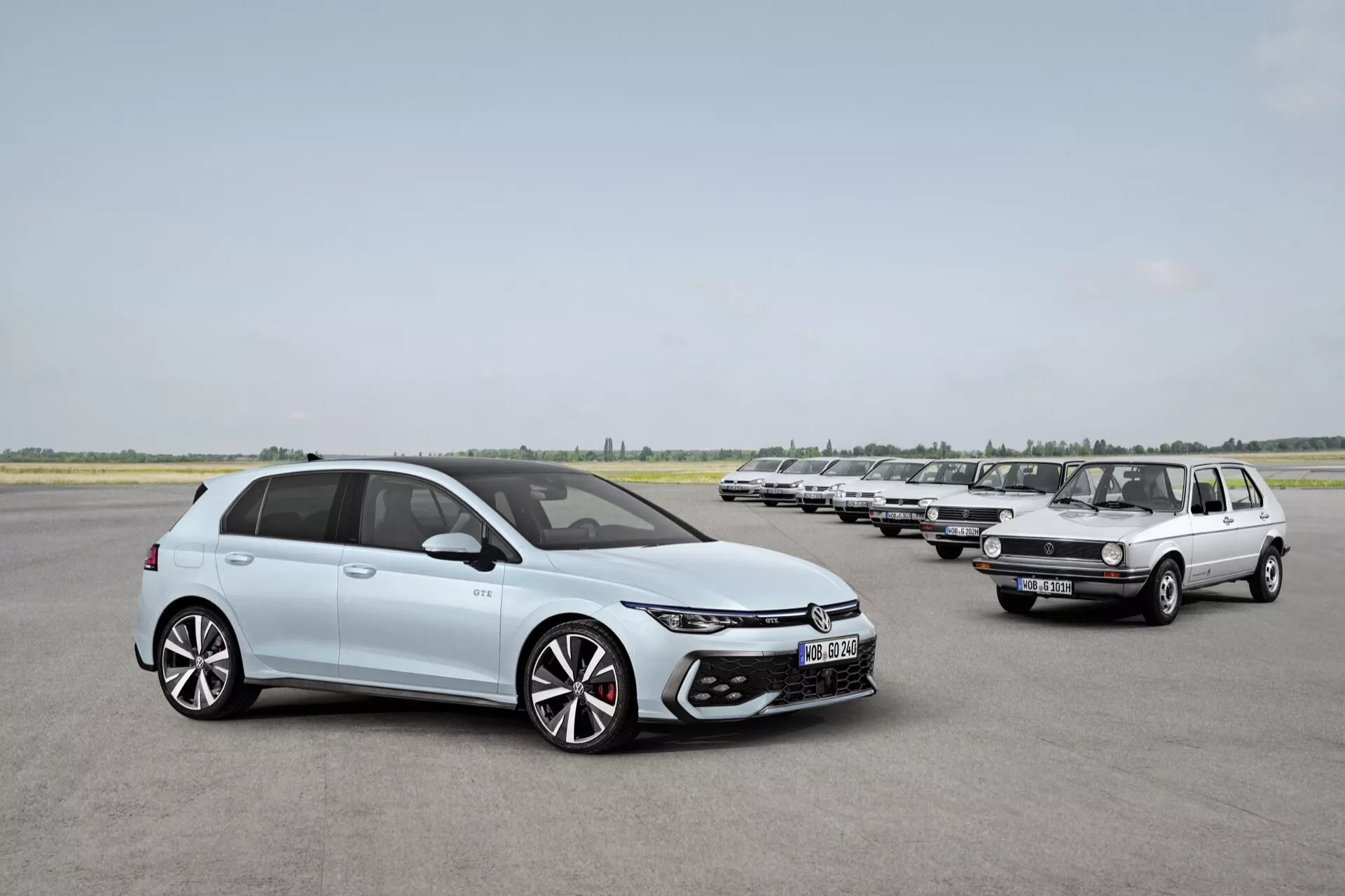 VW Golf 2024 (VIII-Facelift) w jasnobłękitnym kolorze, nowoczesny hatchback z LED-owymi reflektorami, dużym wlotem powietrza, 18+ calowymi dwukolorowymi felgami ze stopu i eleganckimi liniami nadwozia, prezentujący ewolucję w projektowaniu samochodów obok starszego modelu VW Golf na pasie startowym.