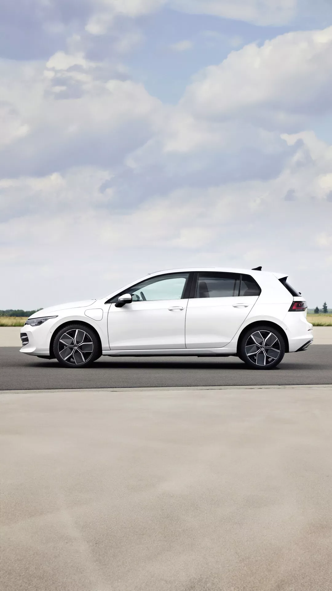 Widok z boku Volkswagen Golf VIII Facelift 2024 ukazujący sportowe felgi aluminiowe, opadający dach i białe wykończenie lakieru w jasny dzień na zewnątrz