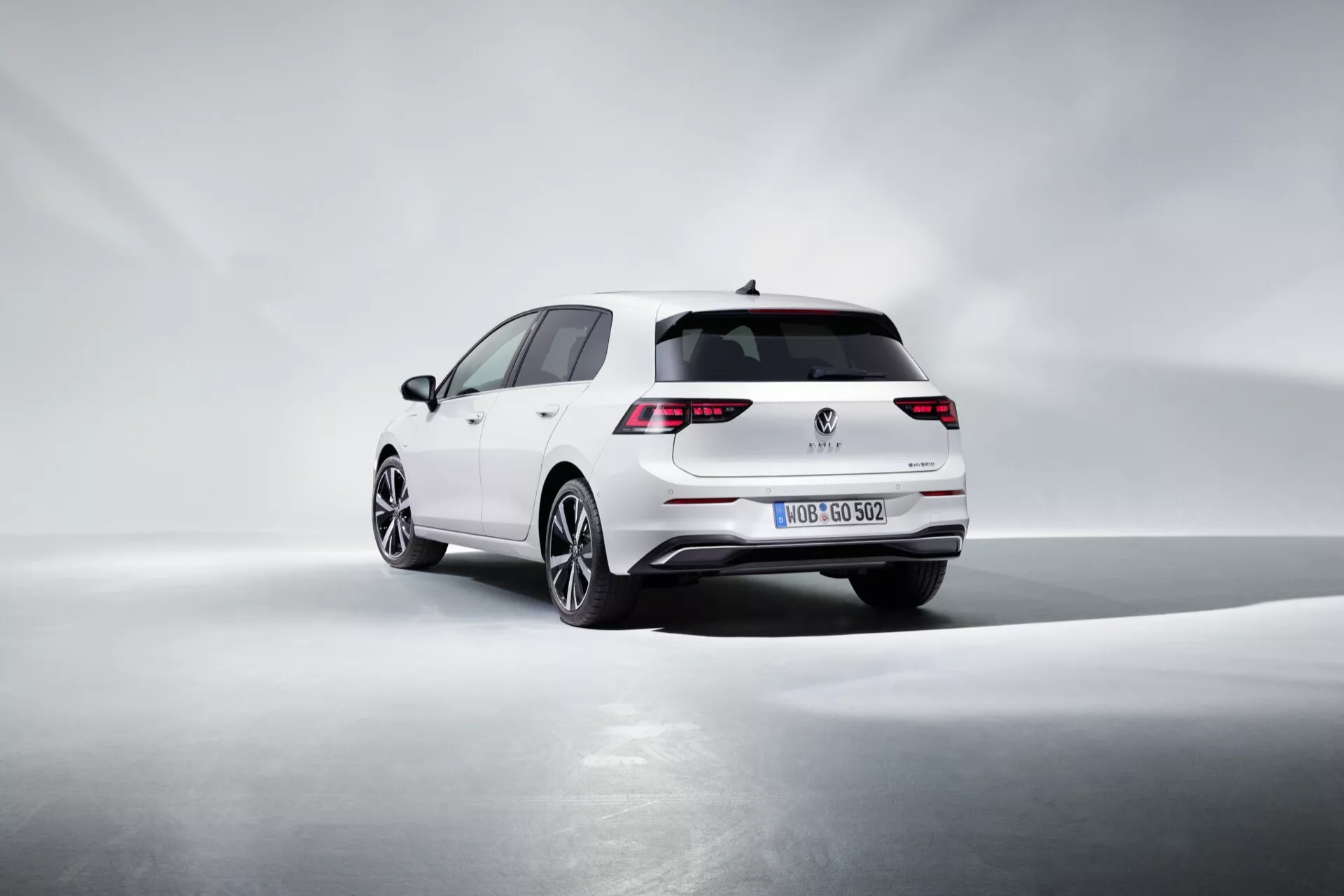 Volkswagen Golf VIII facelifting 2024 w kolorze białym, prezentujący diody LED w tylnych światłach, sportowy tylny zderzak z zintegrowaną końcówką wydechową, konstrukcję hatchback, alufelgi wysokiej jakości oraz potencjalną technologię asysty parkingowej, wszystko uchwycone w dynamicznym trzykwartalnym widoku z tyłu z miękkim oświetleniem podkreślającym linie designu na jednolitym tle.