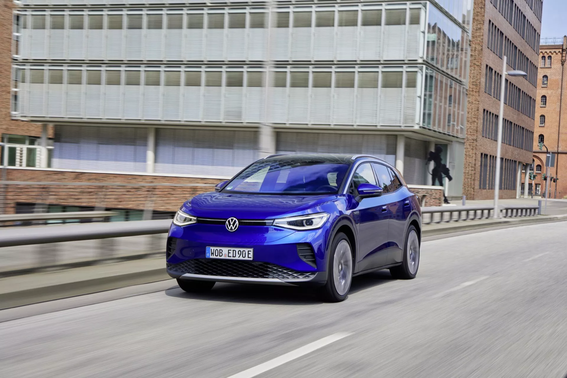 Niebieski VW ID.4 z 2020 roku, 1 generacja, prezentujący aerodynamiczny design i nowoczesne funkcje technologiczne, jadący po miejskiej drodze