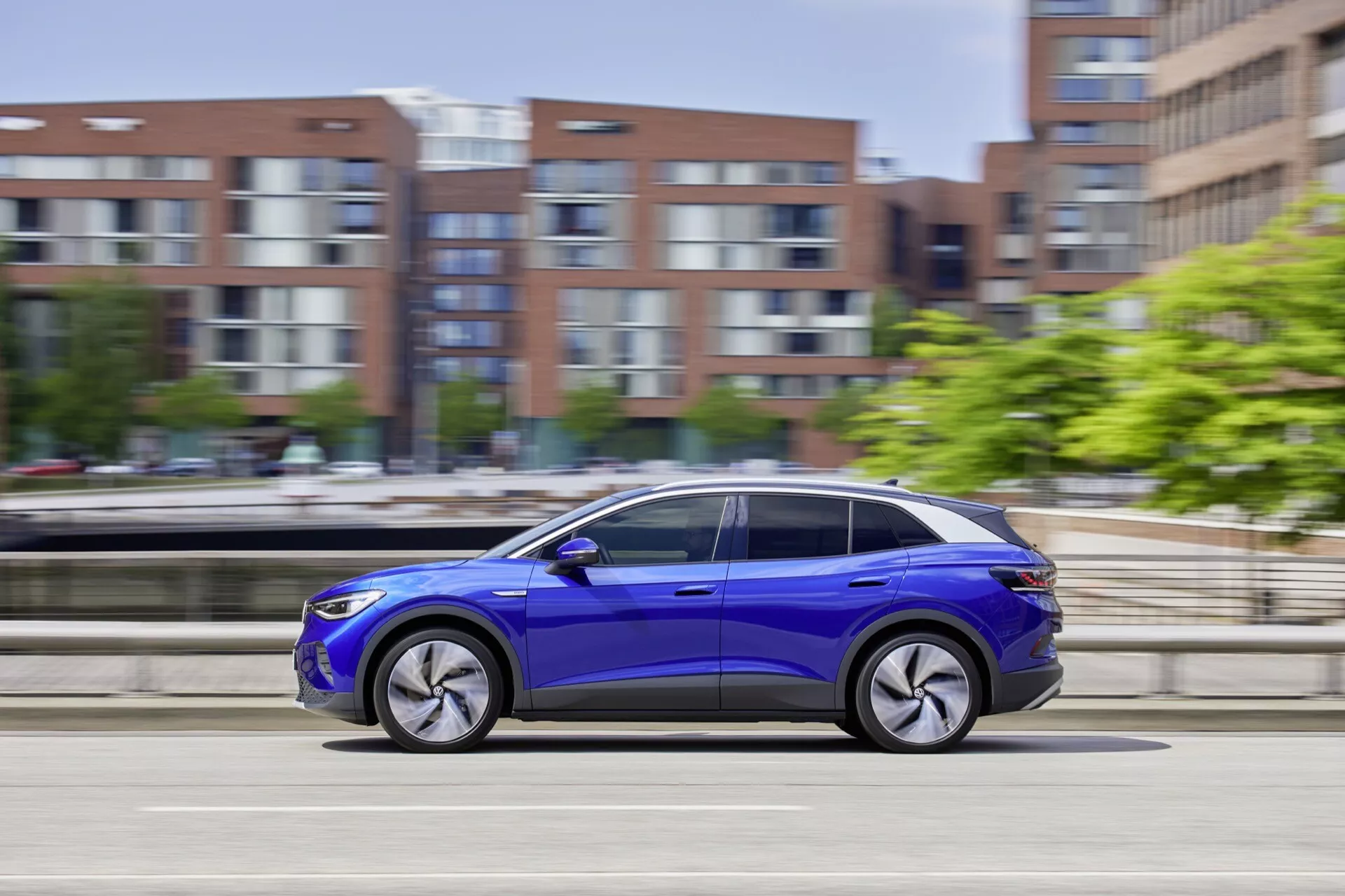 Dynamiczny boczny profil VW ID.4 2020 w ruchu, prezentujący żywy niebieski kolor, felgi ze stopów i nowoczesne cechy wzornictwa na rozmytym tle