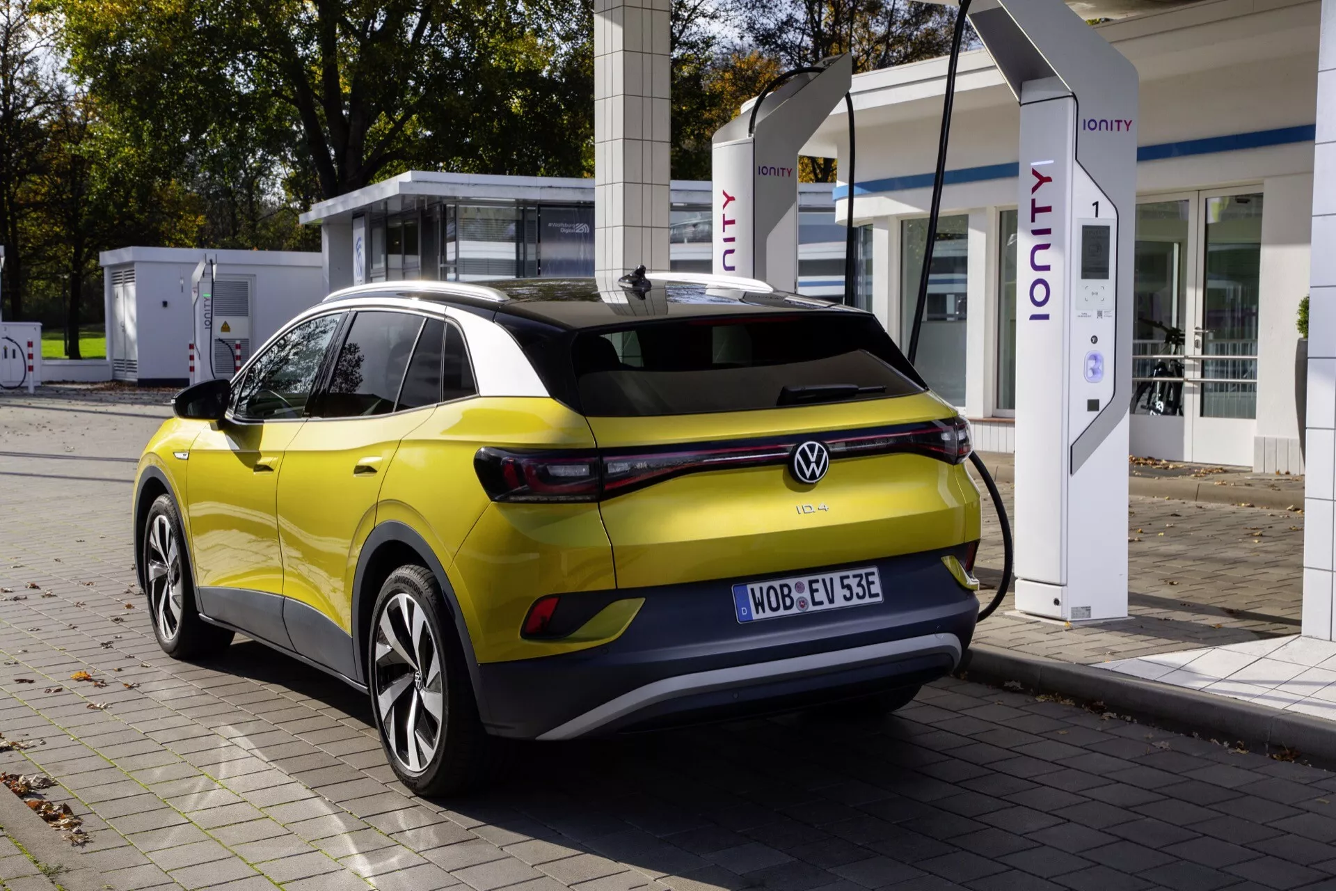 Nowoczesny hatchback elektryczny przy stacji ładowania IONITY z żółtym nadwoziem i czarnym dachem, widziany z trójkwartalnego tylnego kąta podkreślającego aerodynamiczny design i zaawansowaną technologię oświetleniową