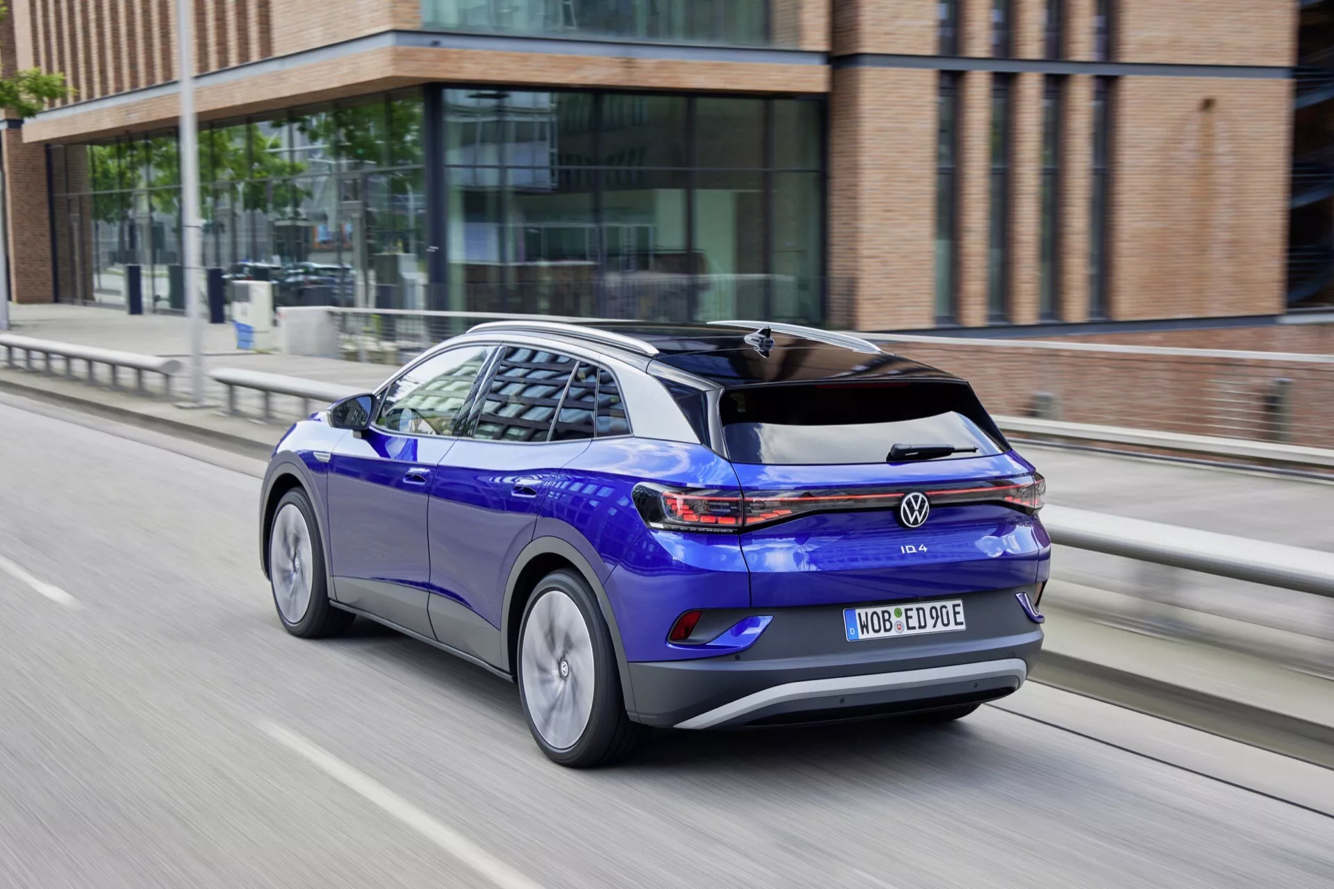 Volkswagen ID.4 1. Generacja 2020 w Błyszczącym Niebieskim, Widok Z Tyłu Z Levej Strony w Ruchu z Aerodynamiczną Sylwetką, Tylnymi Światłami LED, Felgami Aluminiowymi i Cechami Pojazdu Elektrycznego