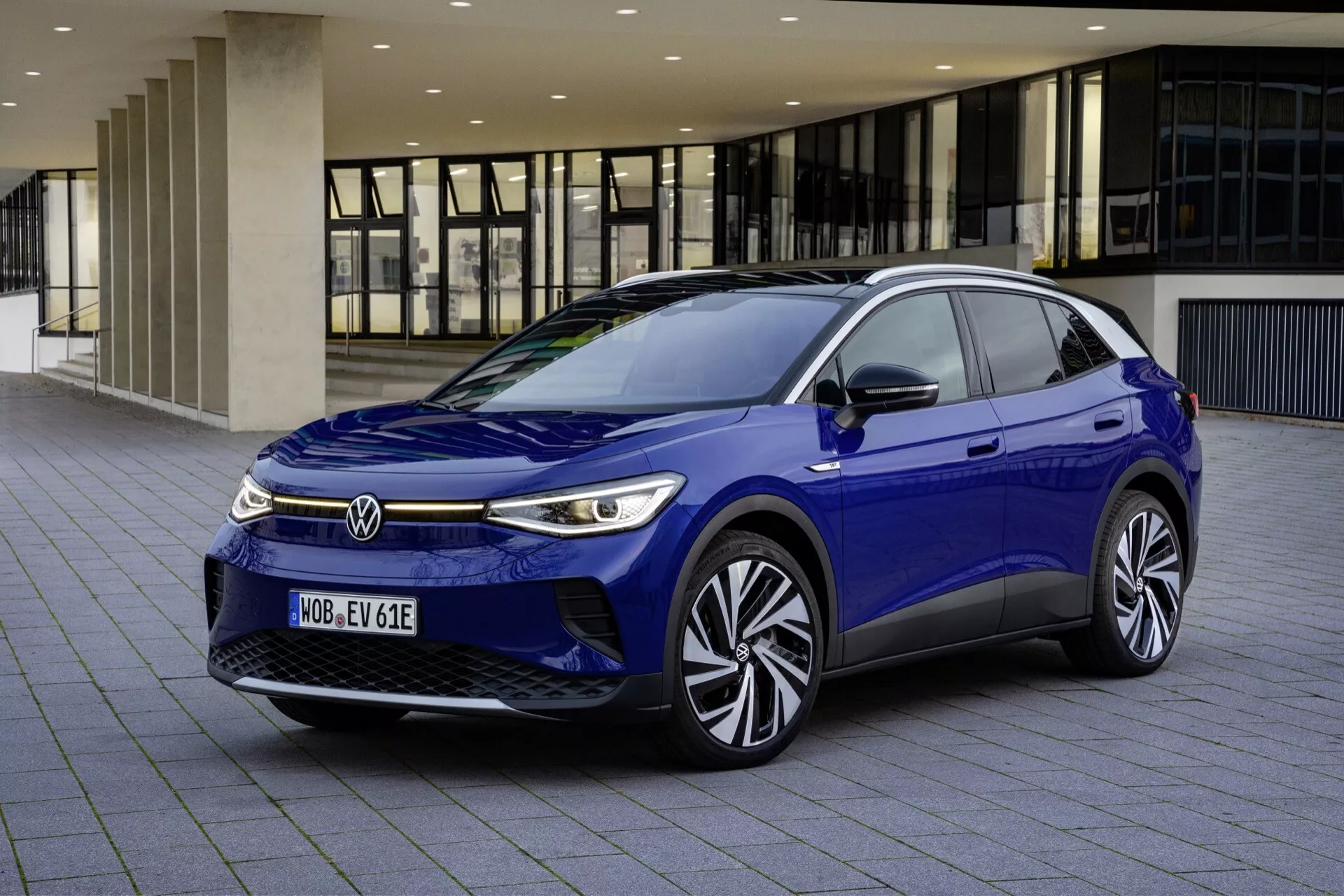 VW ID.4 1. generacji 2020 w kolorze niebieskim - Nowoczesny hatchback elektryczny z dynamiczną przednią kratą, eleganckimi LED-owymi reflektorami z zintegrowanymi światłami do jazdy dziennej, aerodynamicznym designem maski i przedniej szyby, prezentujący zaawansowaną technologię i stylowe felgi aluminiowe, uchwycony z perspektywy trzy czwartej z przodu w miejskim otoczeniu
