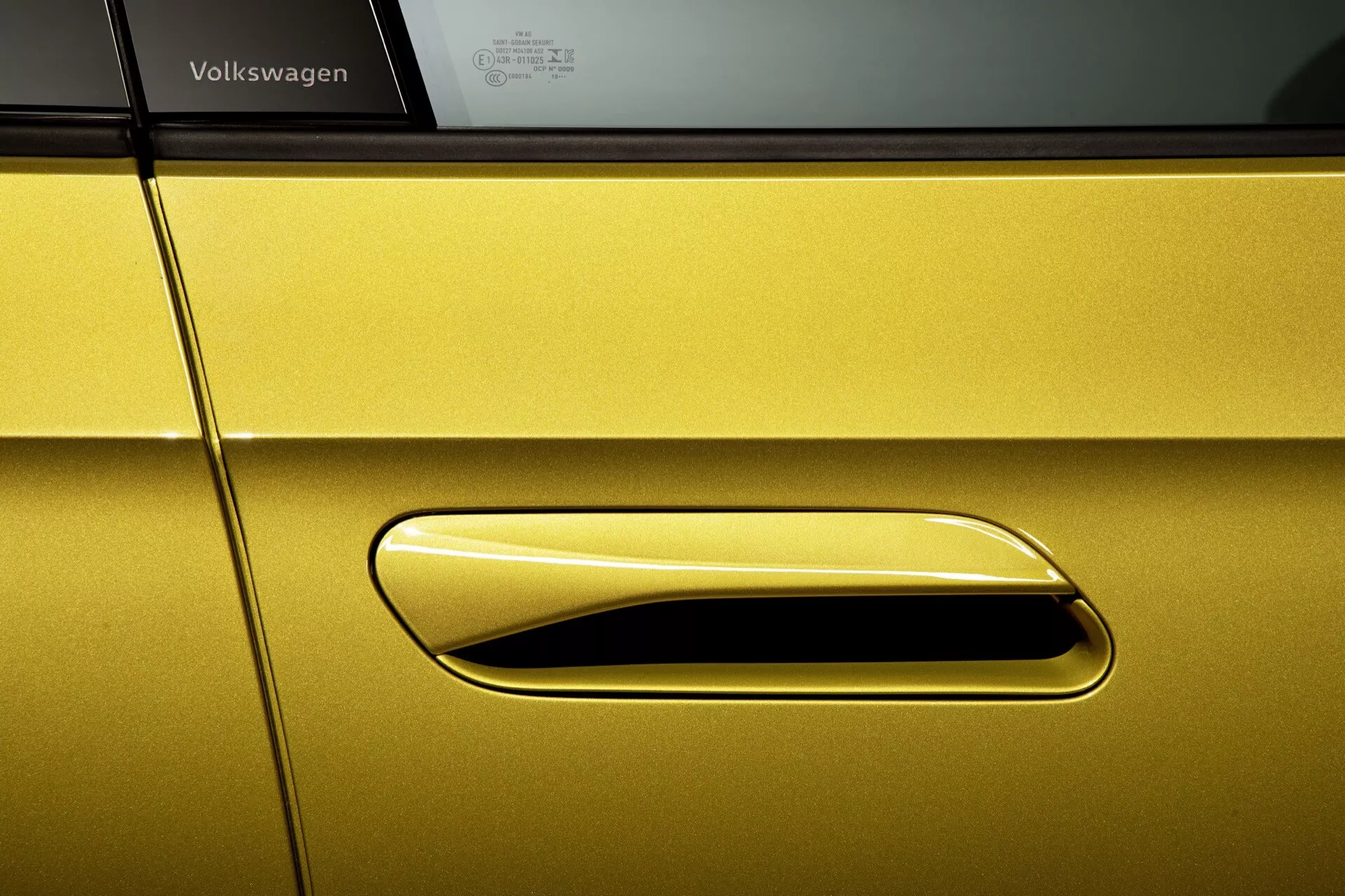 Zbliżony widok na profil boczny jaskrawożółtego Volkswagena ID.4 2020, ukazujący elegancką, wpuszczaną klamkę drzwi i przyciemniane okno z czarną obramówką, odzwierciedlający nacisk na nowoczesny aerodynamiczny design, wysokiej jakości lakier oraz zaawansowane funkcje, takie jak dostęp bezkluczykowy.