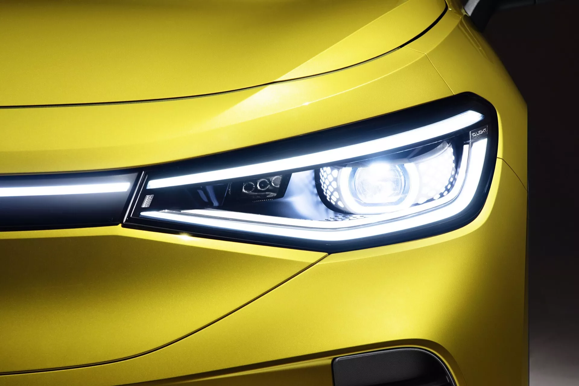 Zbliżenie na przedni narożnik VW ID.4 z 2020 roku, pokazujące design świateł LED, światła dzienne i fragment metalicznie żółtej kraty i zderzaka